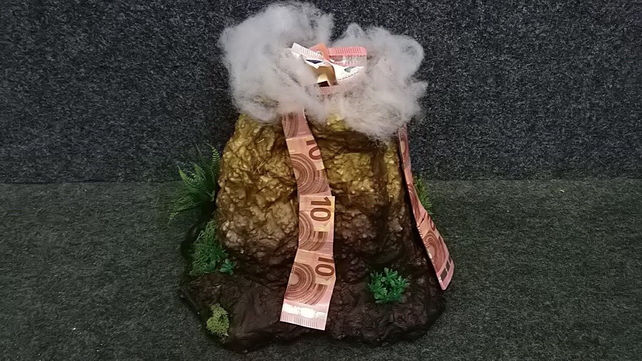 Auf einem Tisch steht ein Vulkan aus Geld.