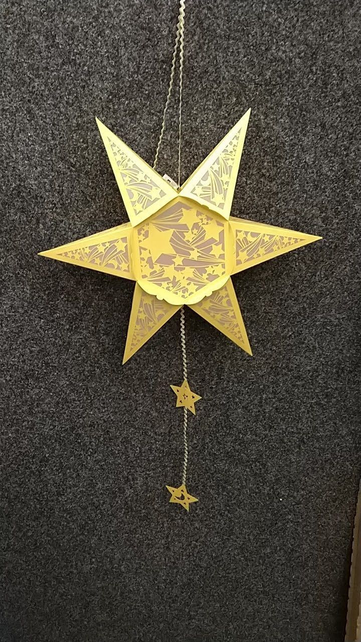 Ein gelber Stern hängt an einer Schnur auf schwarzem Hintergrund.