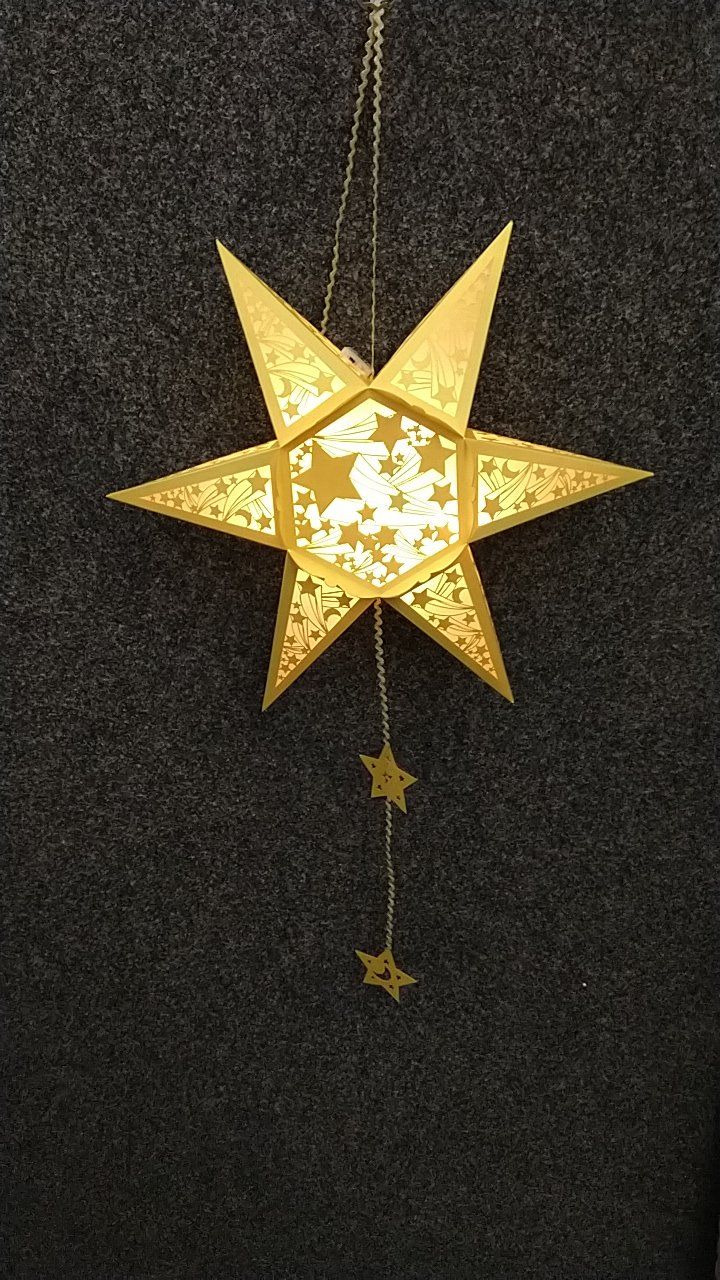 Ein goldener Stern hängt an einer Schnur auf einem schwarzen Hintergrund.