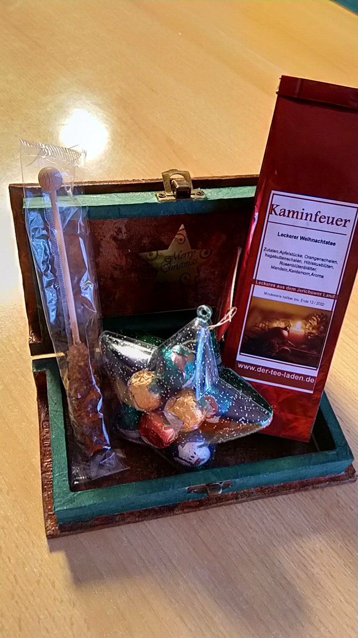 Eine Holzschachtel gefüllt mit Süßigkeiten und einem Beutel Tee.