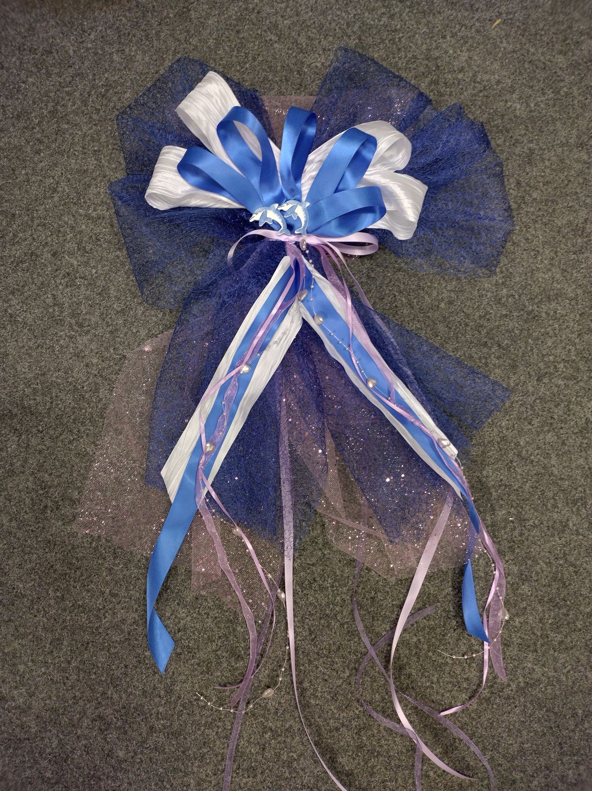 Auf einem Teppich liegt eine blau-weiße Schleife mit Bändern.