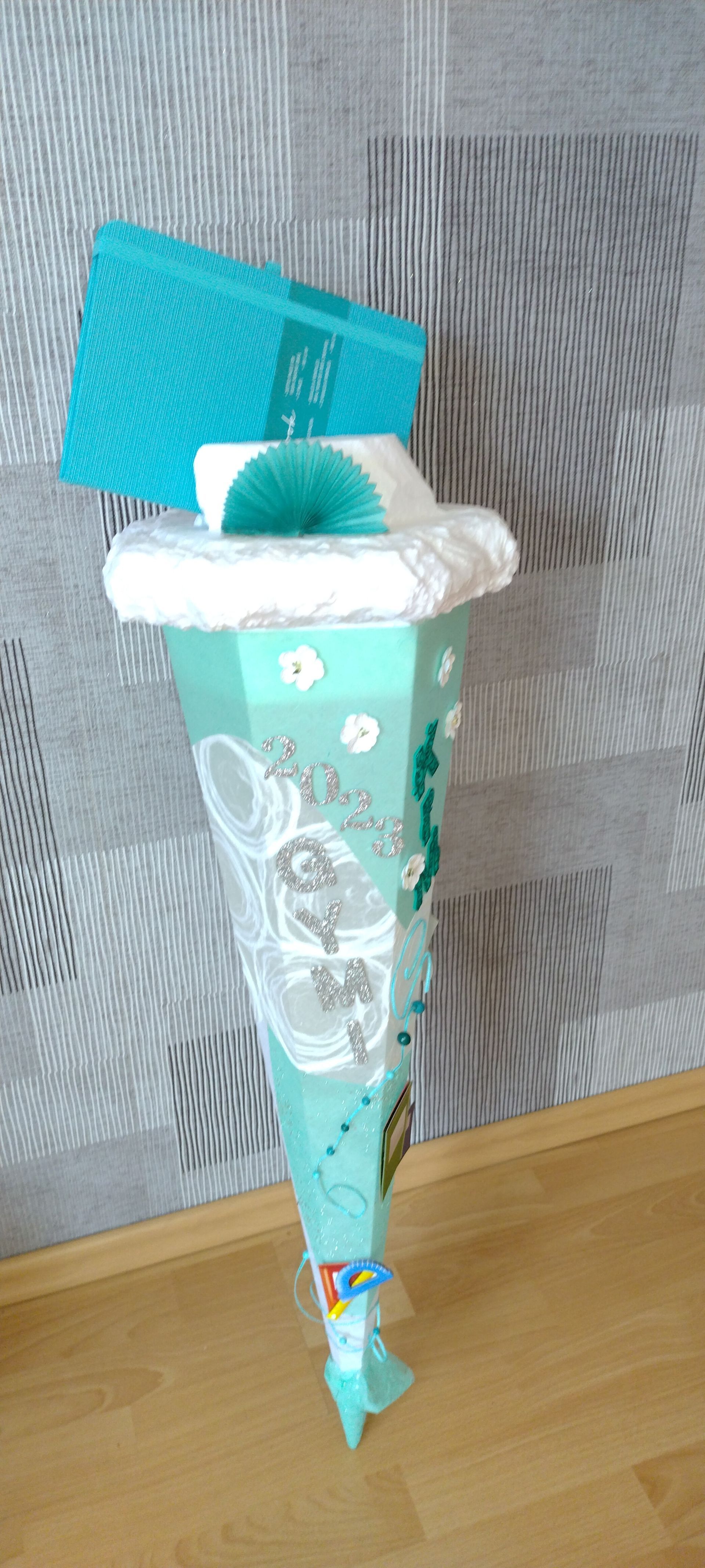 Ein blau-weißer Kegel hängt an einer Schnur auf einem Holzboden.