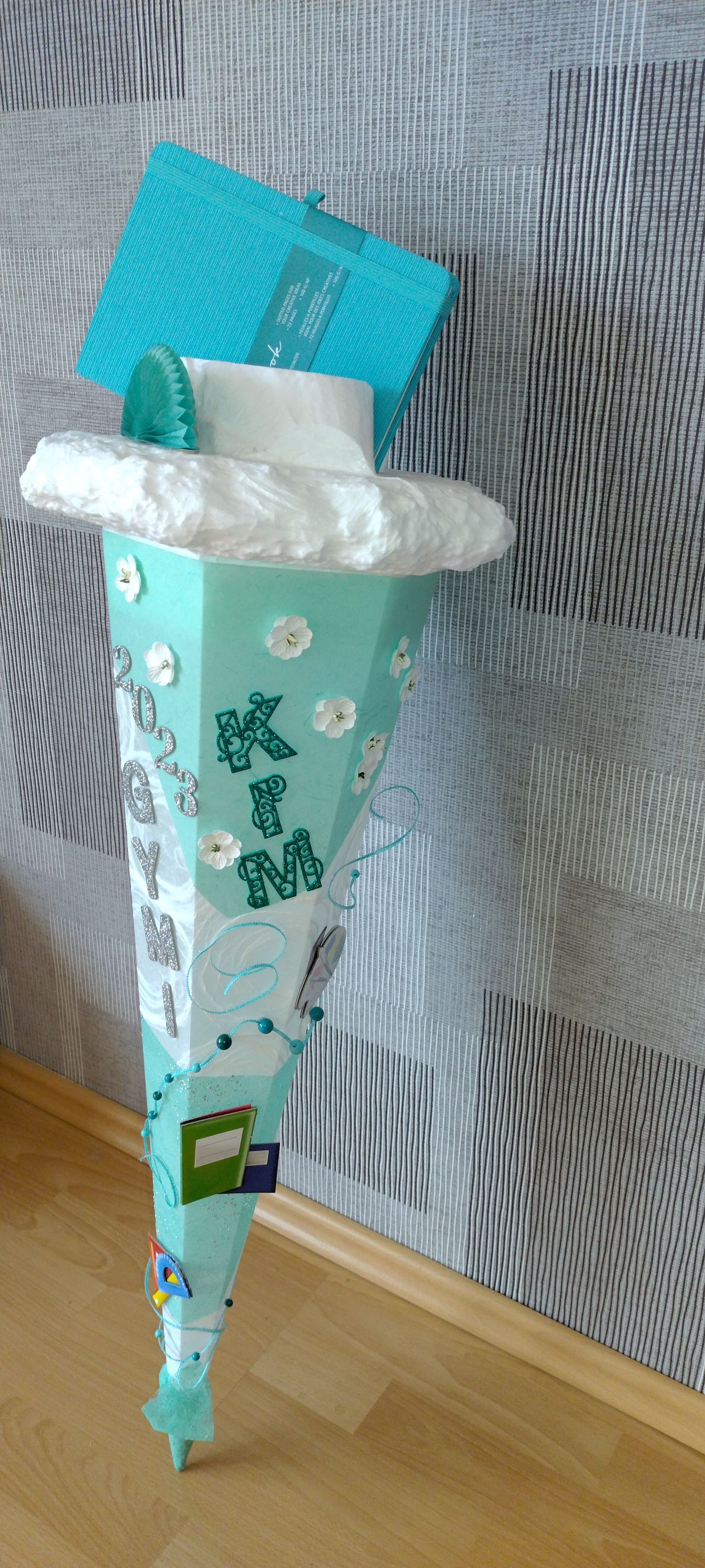 Ein grüner Kegel mit einem Haus darauf steht auf einem Holzboden.