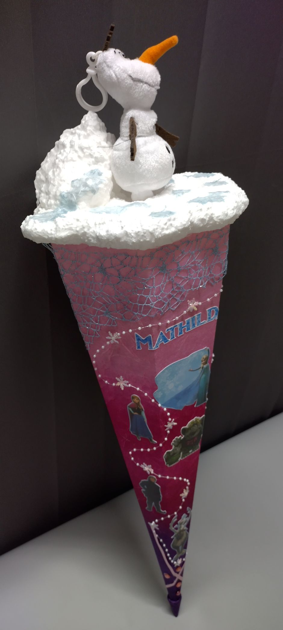 Eine Eistüte mit einem Schneemann obendrauf.