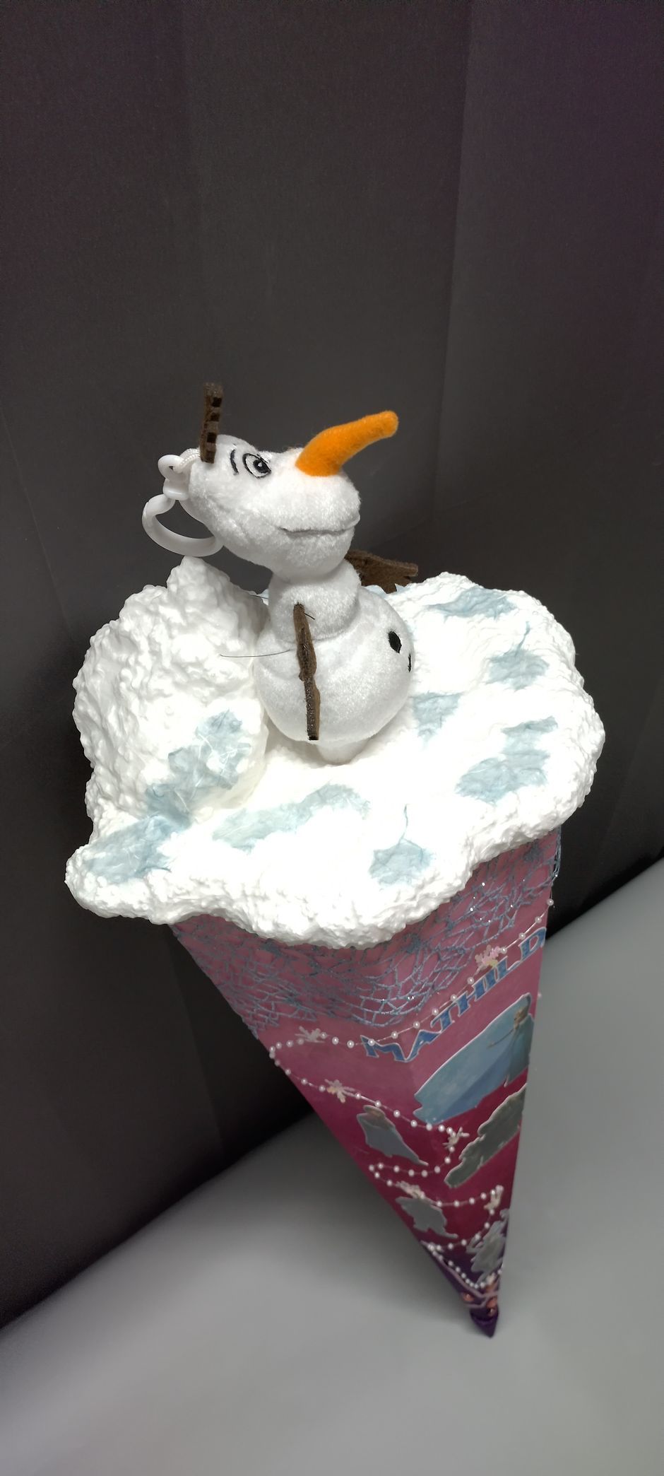 Eine Eistüte mit einem Schneemann obendrauf.