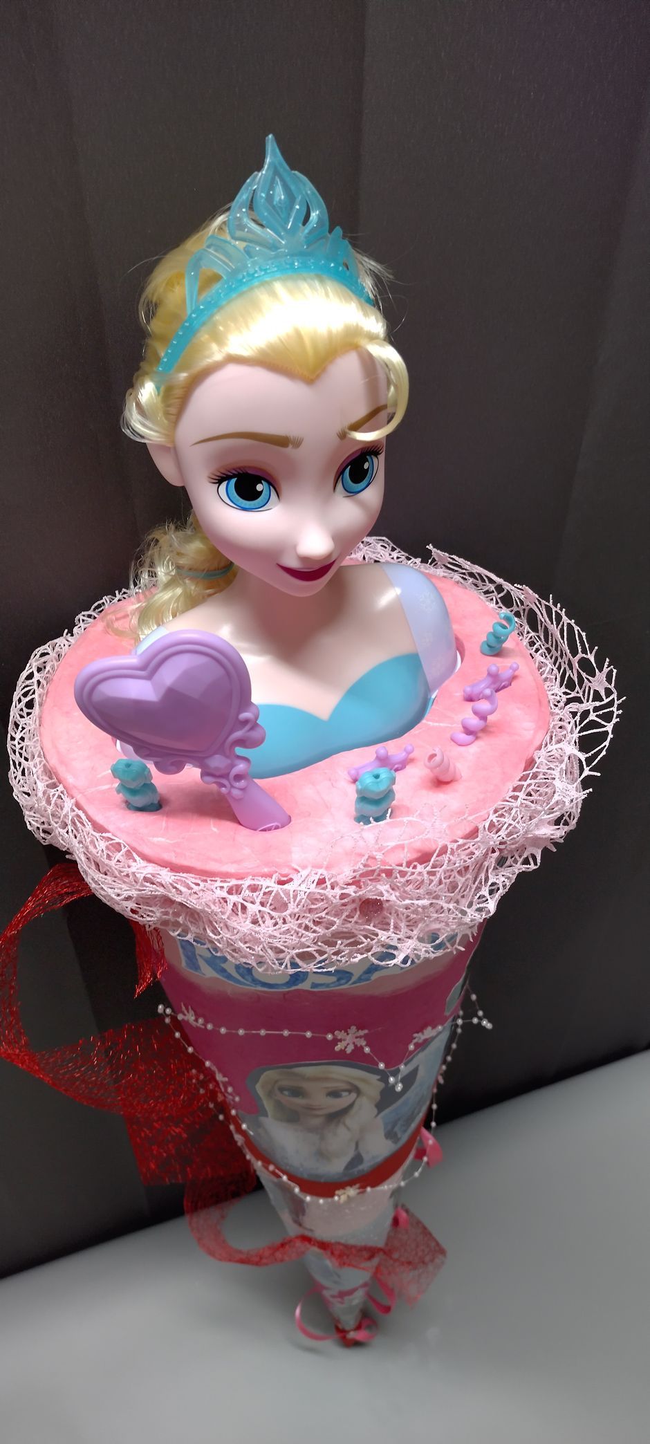 Eine Puppe sitzt auf einem rosa Kegel.