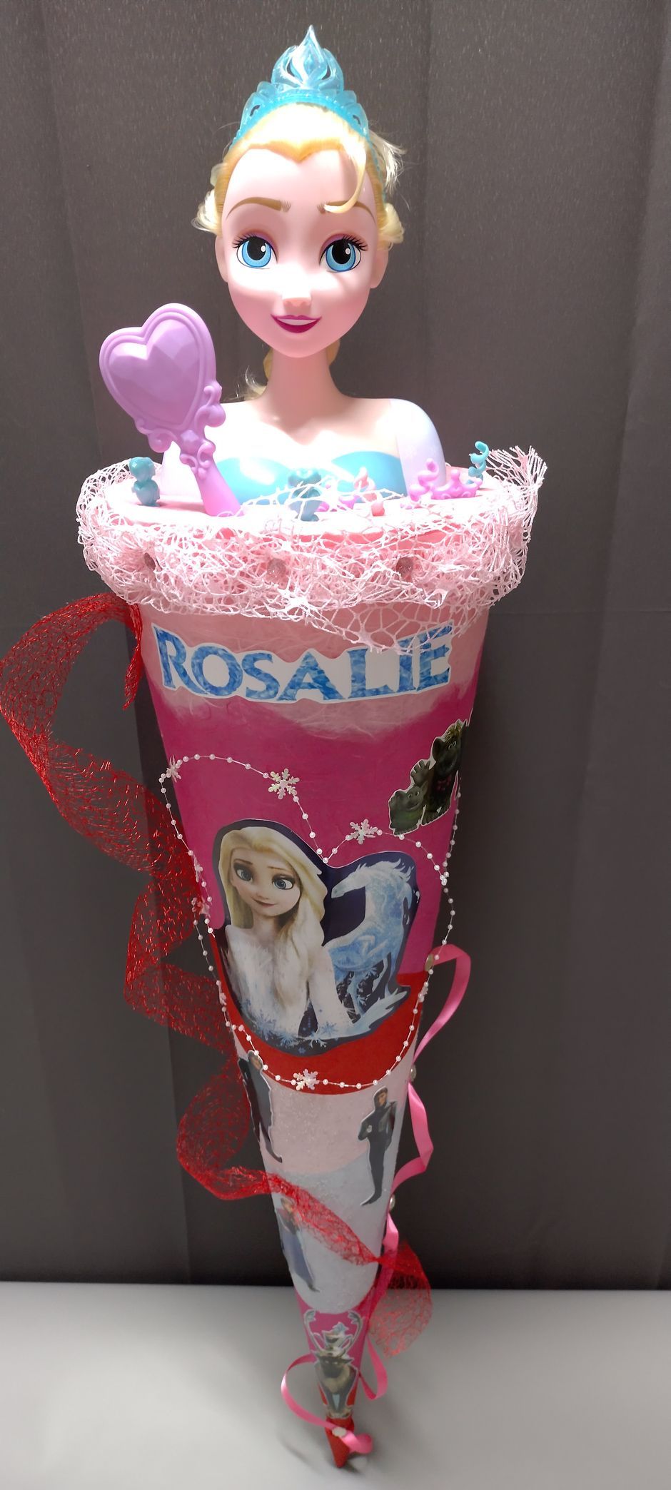 In einer rosa Tüte sitzt eine Puppe mit dem Namen Rosalie darauf.