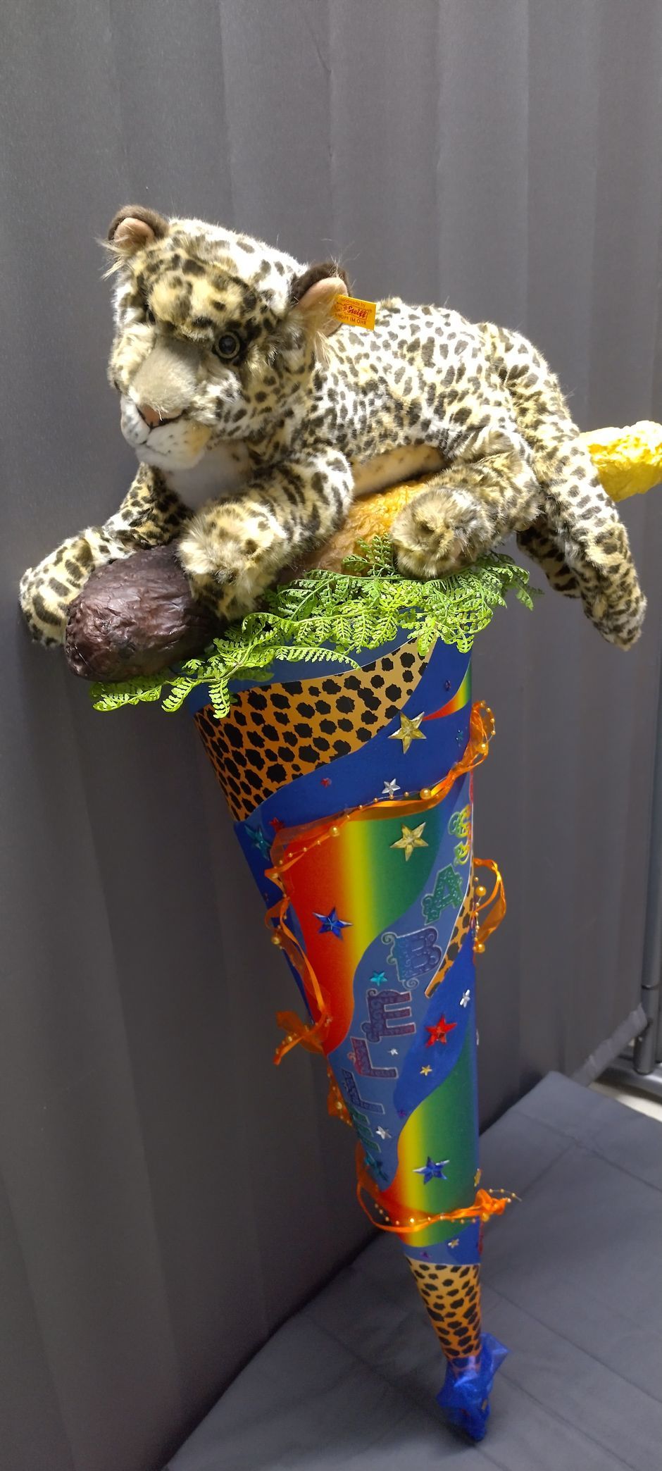 Ein ausgestopfter Leopard liegt auf einem bunten Kegel.