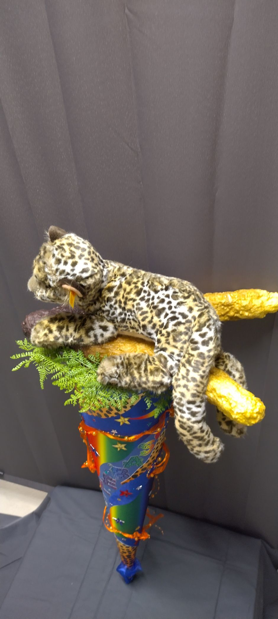 Ein ausgestopfter Leopard liegt auf einem bunten Kegel.