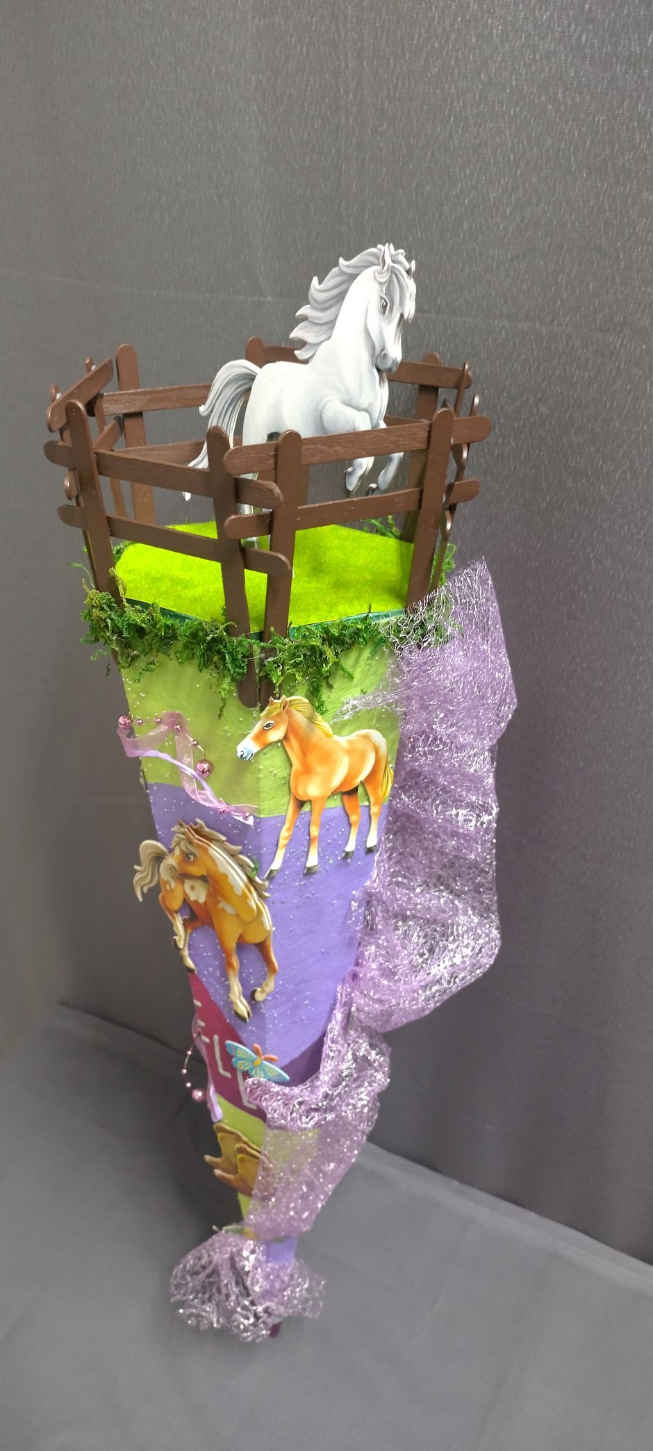 Ein violetter Kegel mit einem weißen Pferd darauf.
