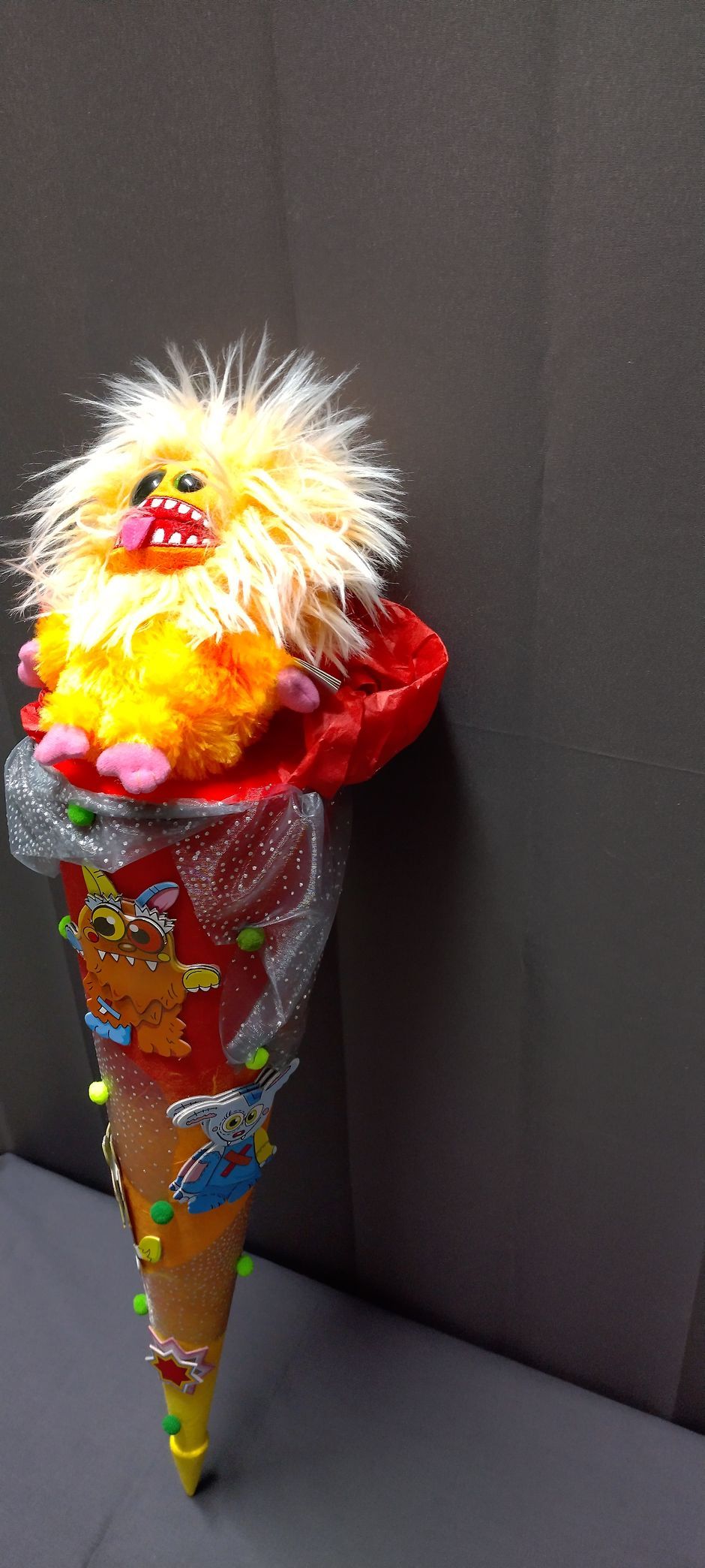 Ein Stofftier sitzt in einem Kegel auf einem Tisch.