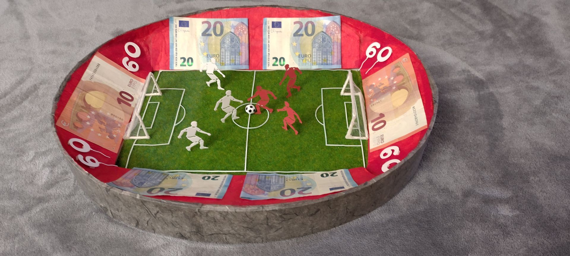 Ein Fußballfeld aus Geld auf einem Teller