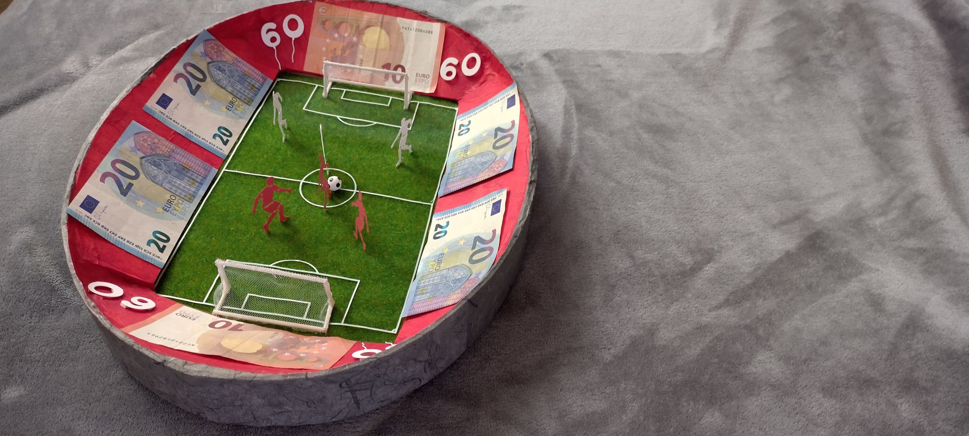 Ein Fußballfeld aus Geld mit der Nummer 60 darauf