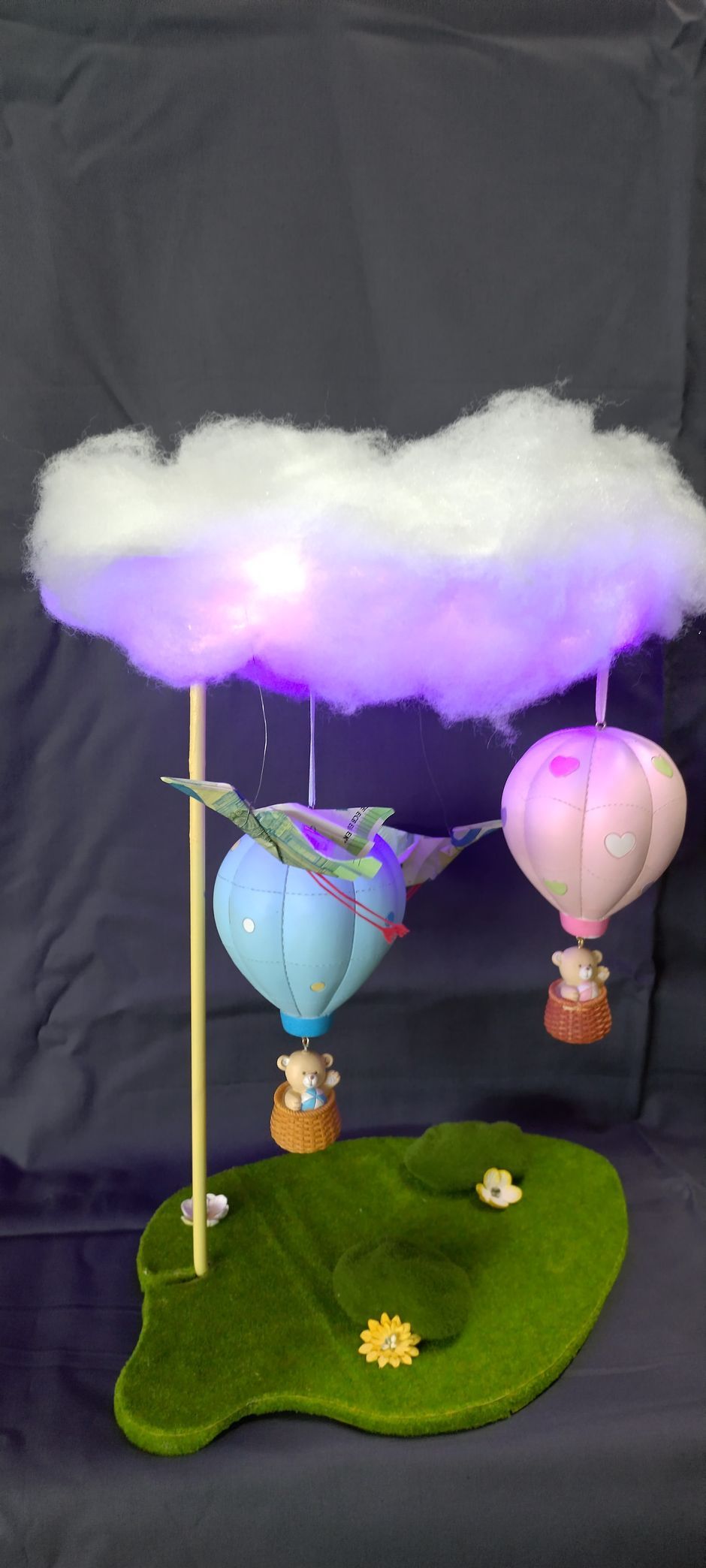 Drei Heißluftballons fliegen über einer Wolke am Himmel.