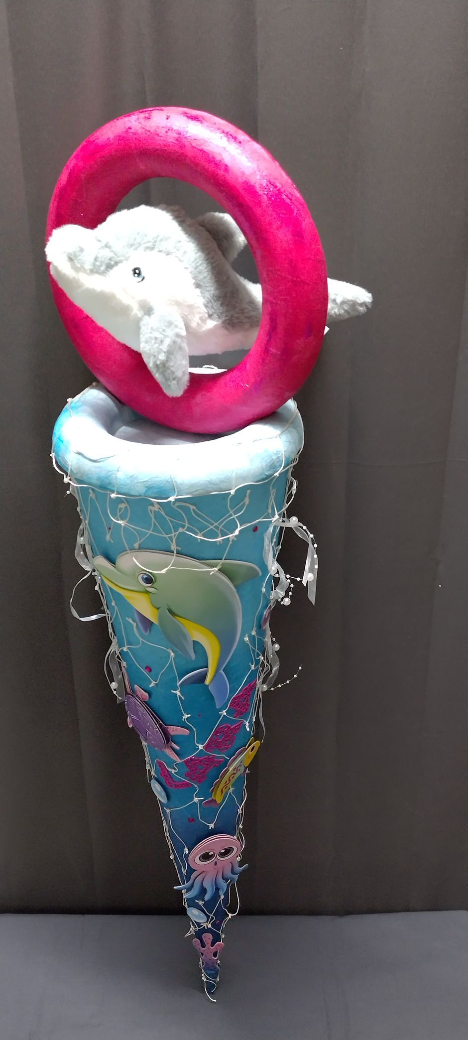 Ein Delphin sitzt mit einem Rettungsring auf der Spitze eines Kegels.