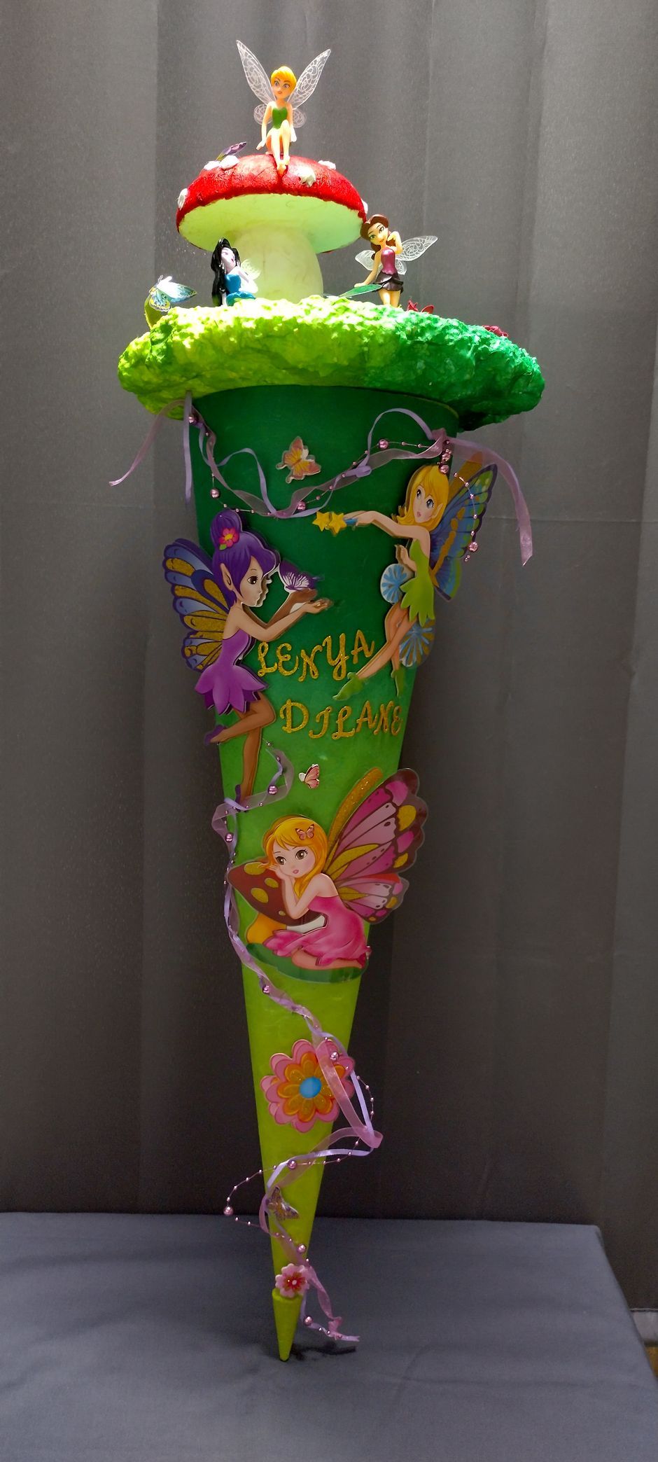 Auf einem Tisch steht ein grüner Kegel mit Feenfiguren darauf.