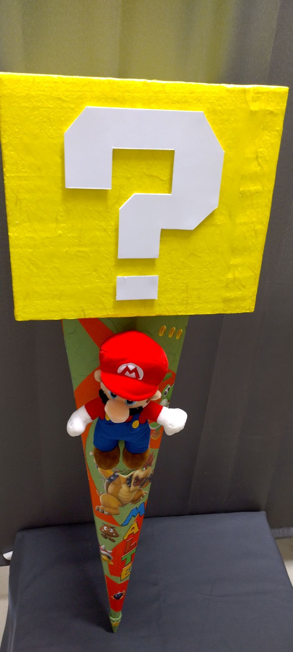 Ein ausgestopfter Mario hält ein gelbes Schild mit einem Fragezeichen darauf.