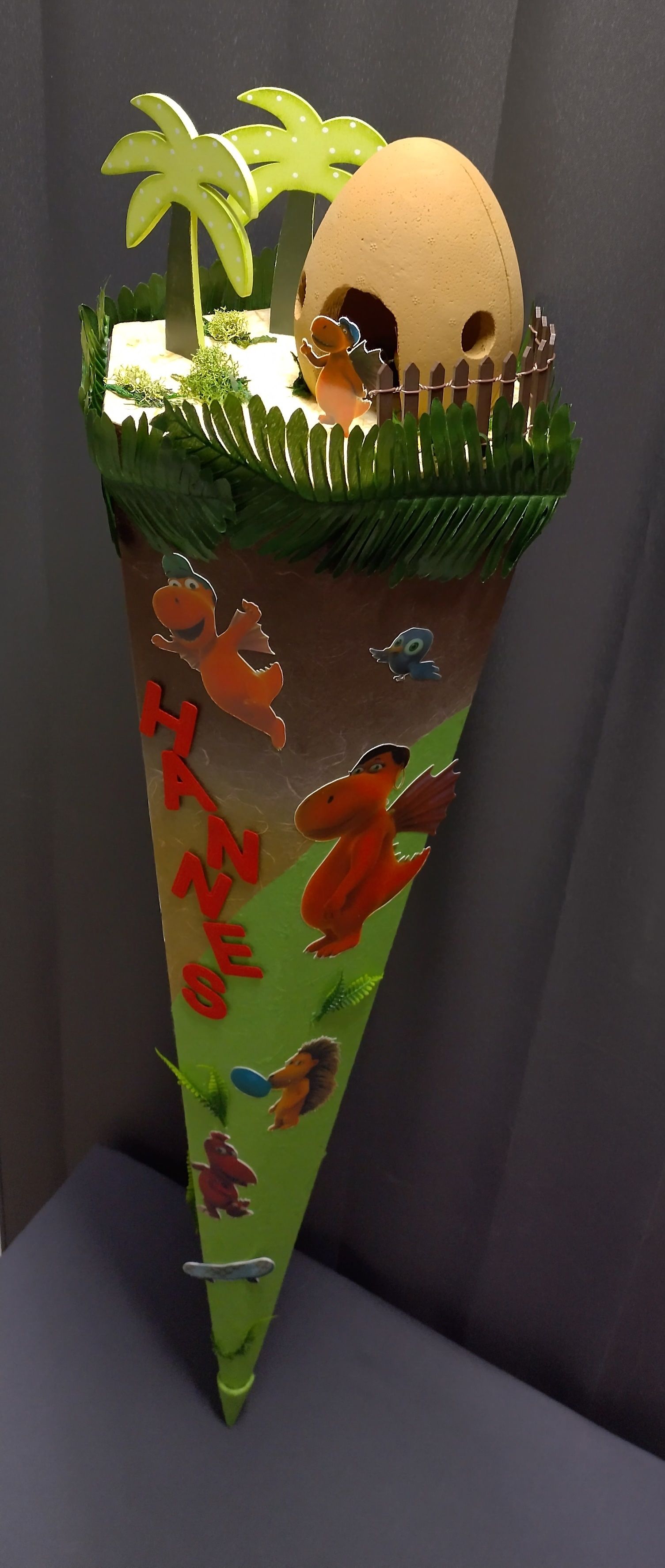 Auf einem Tisch steht ein Kegel mit einem Dinosaurier darauf.