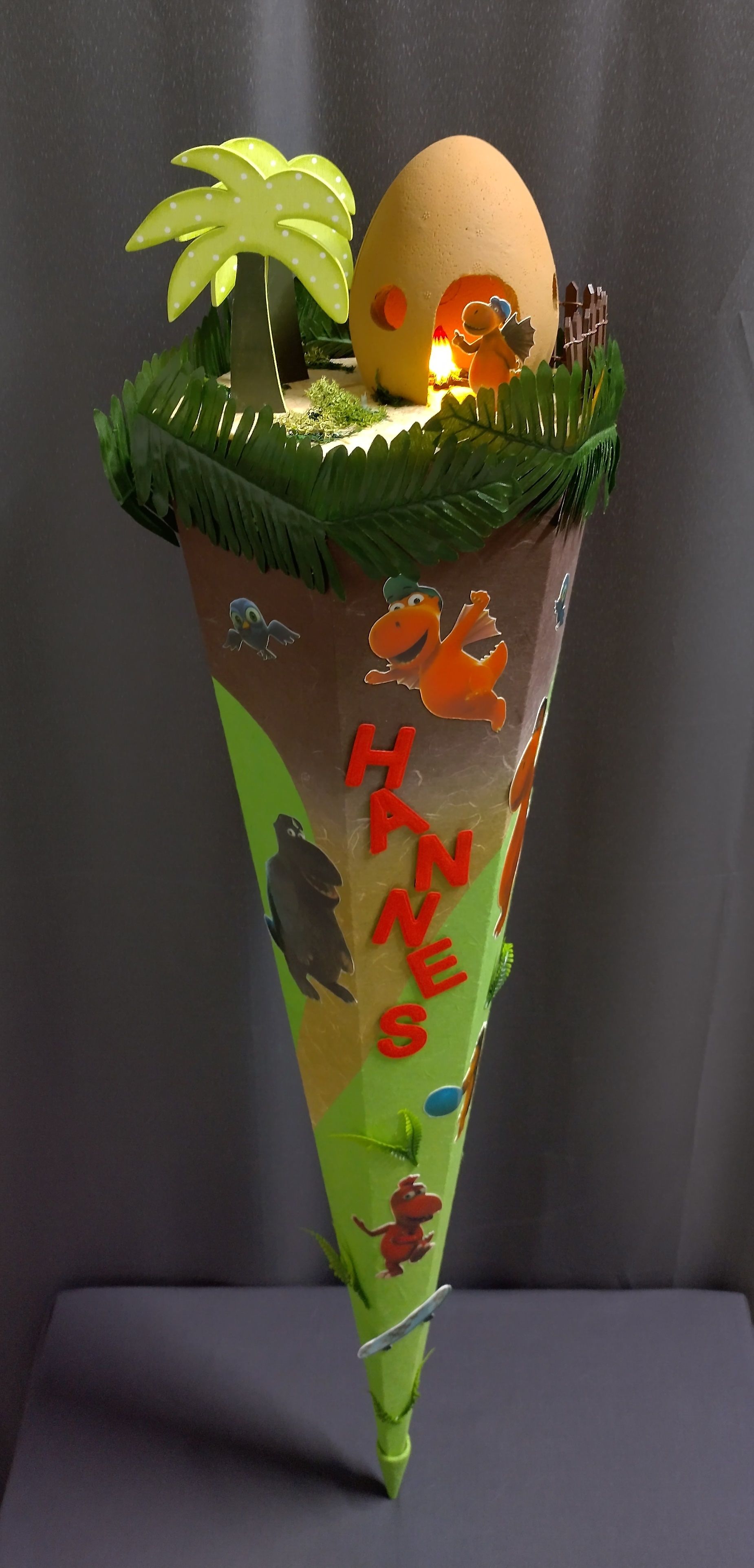 Ein Kegel mit einem Dinosaurier und einem Ei darauf.