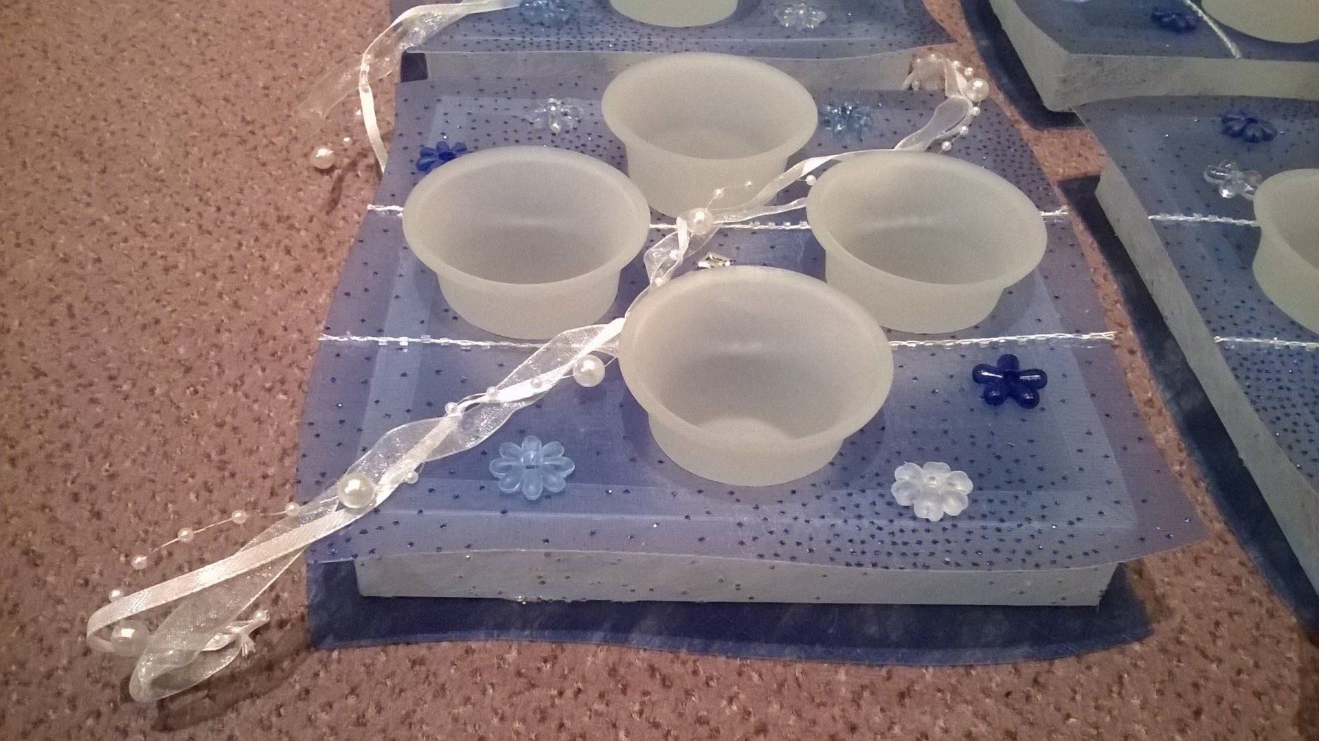 Vier Tassen stehen auf einem blauen Tablett auf einem Tisch.