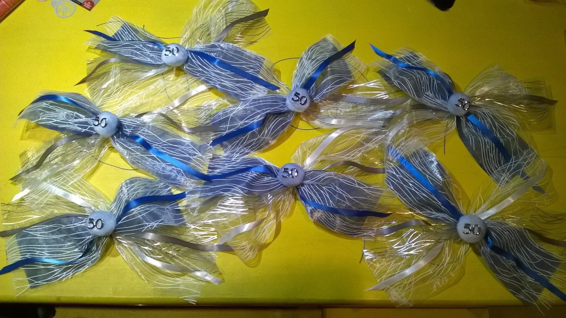 Ein Bündel blauer und silberner Schleifen auf einem gelben Tisch