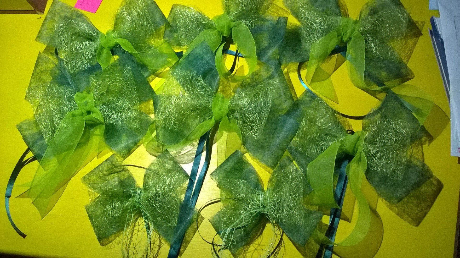 Ein Bündel grüner Schleifen liegt auf einem gelben Tisch.