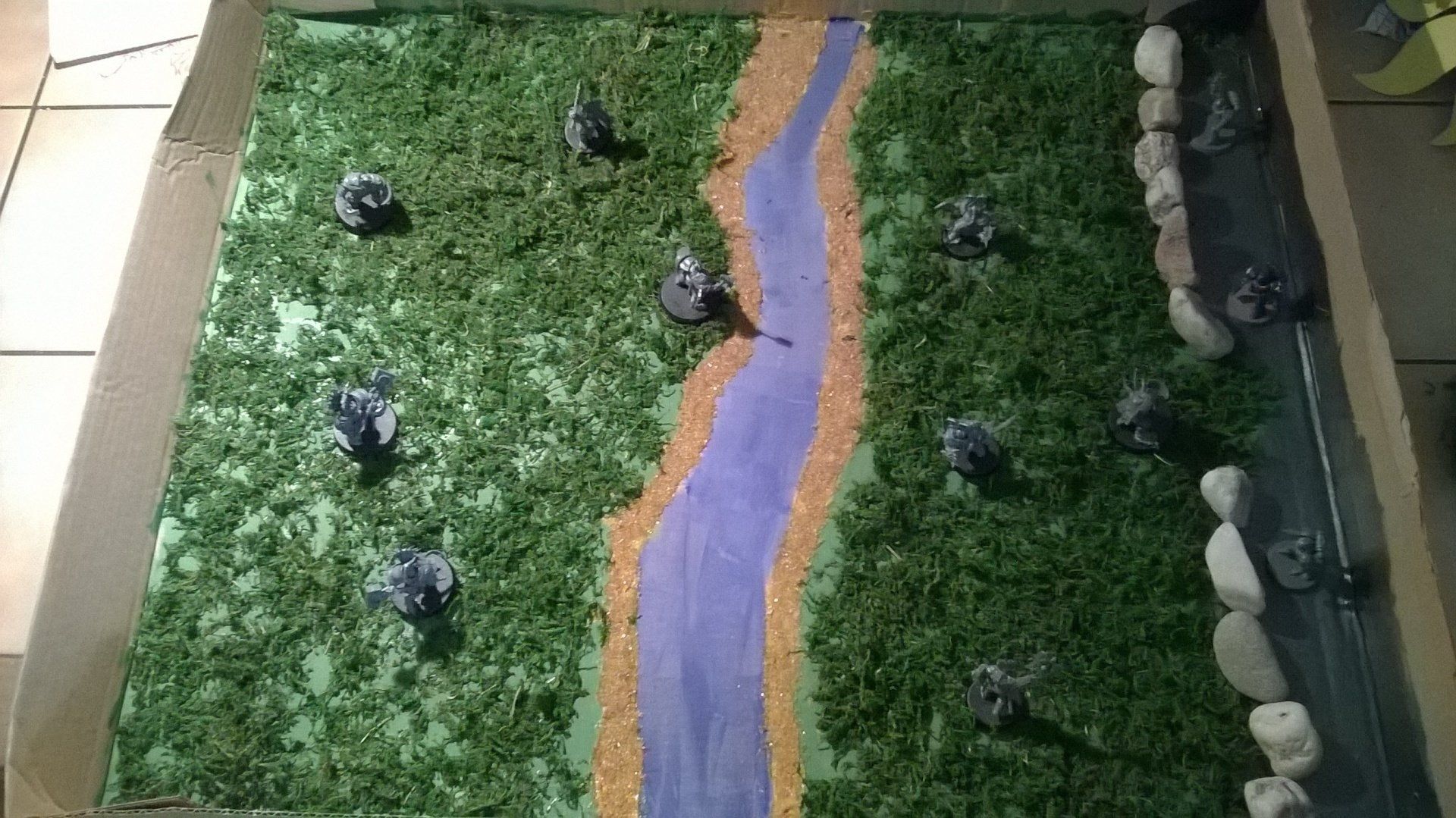 Ein Modell eines Flusses, umgeben von Gras und Felsen auf einem Tisch.