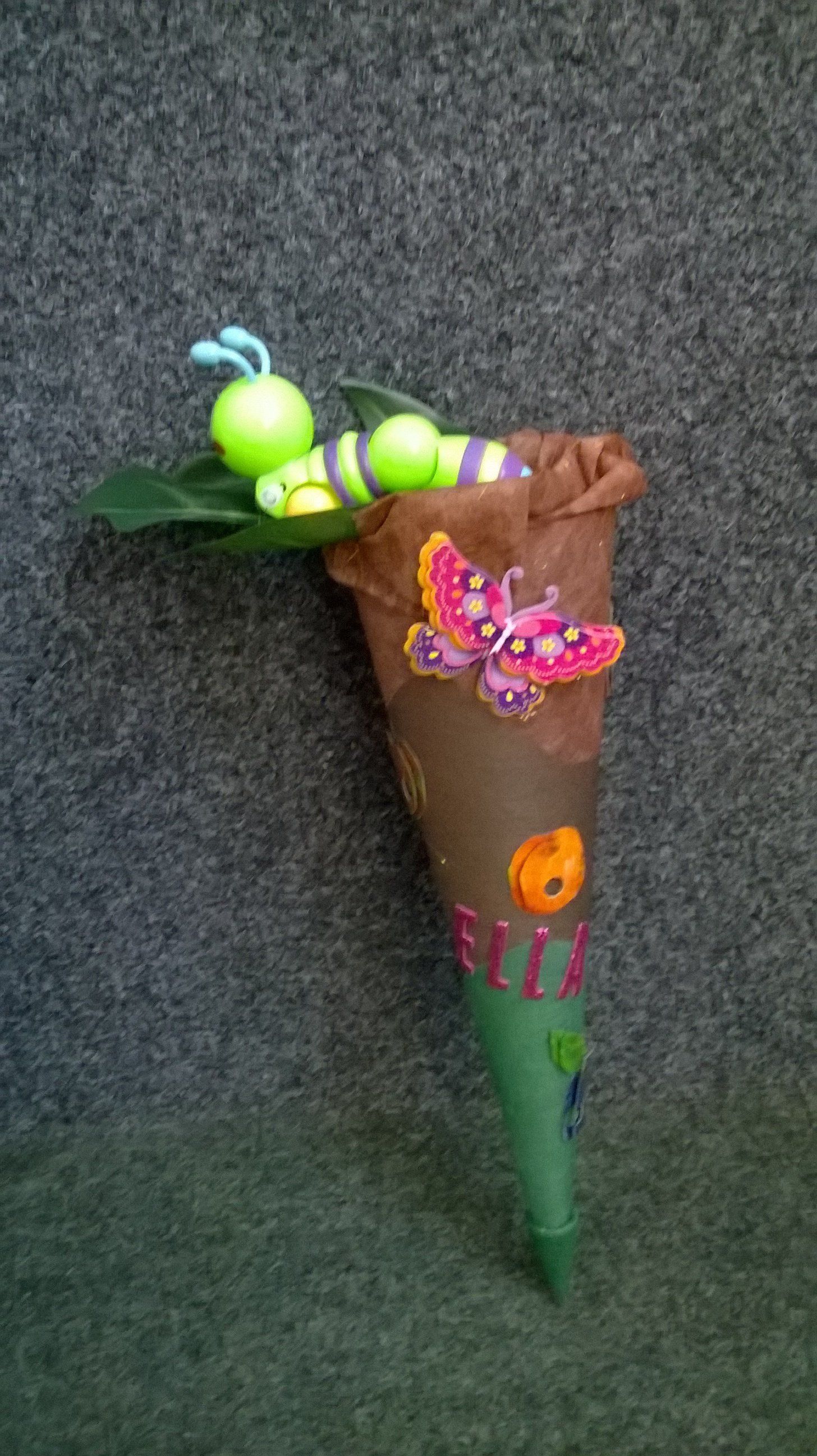 Ein Kegel mit einer Raupe und einem Schmetterling darauf.