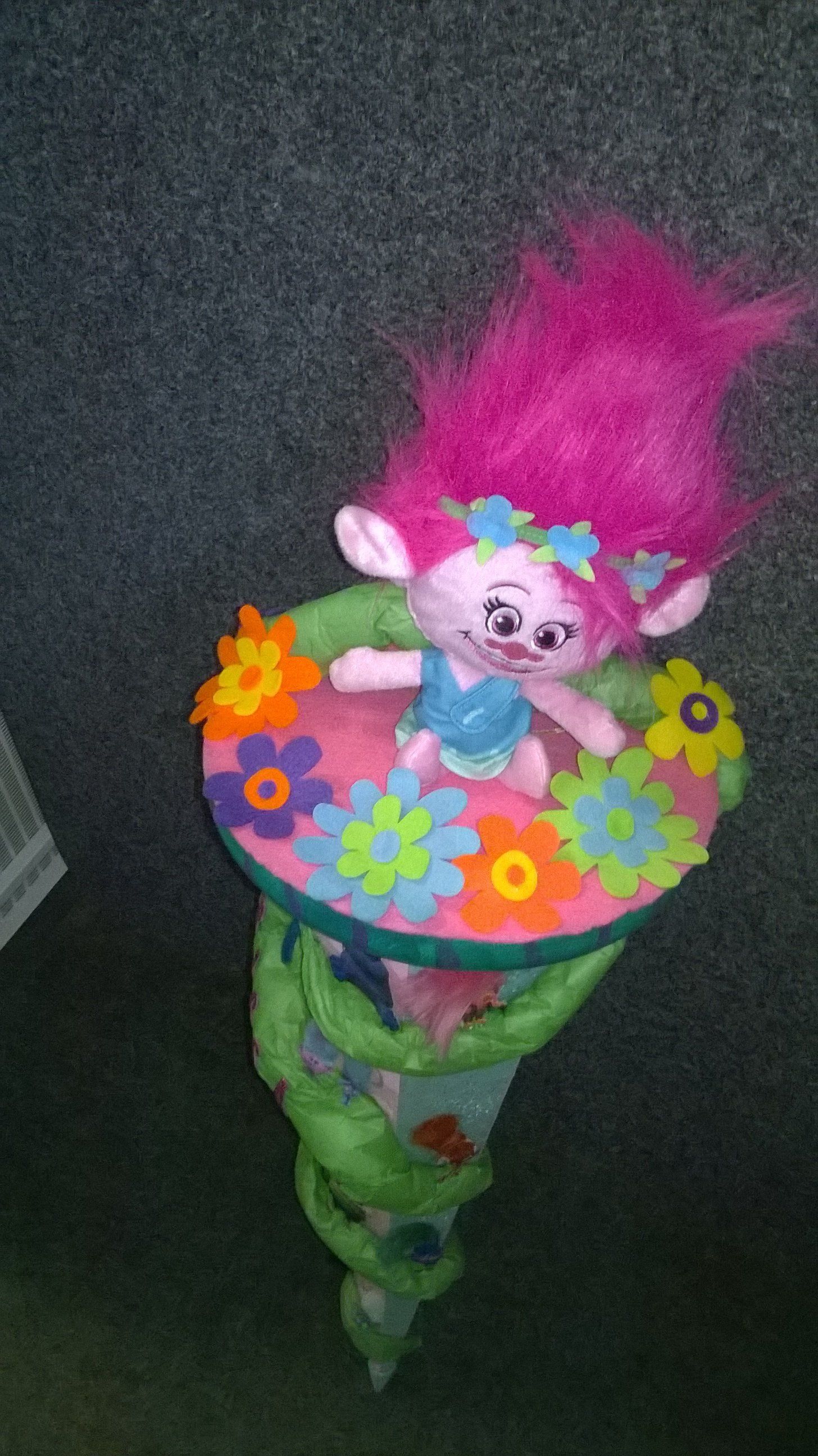 Auf einem Tisch sitzt eine Trollpuppe mit rosa Haaren.