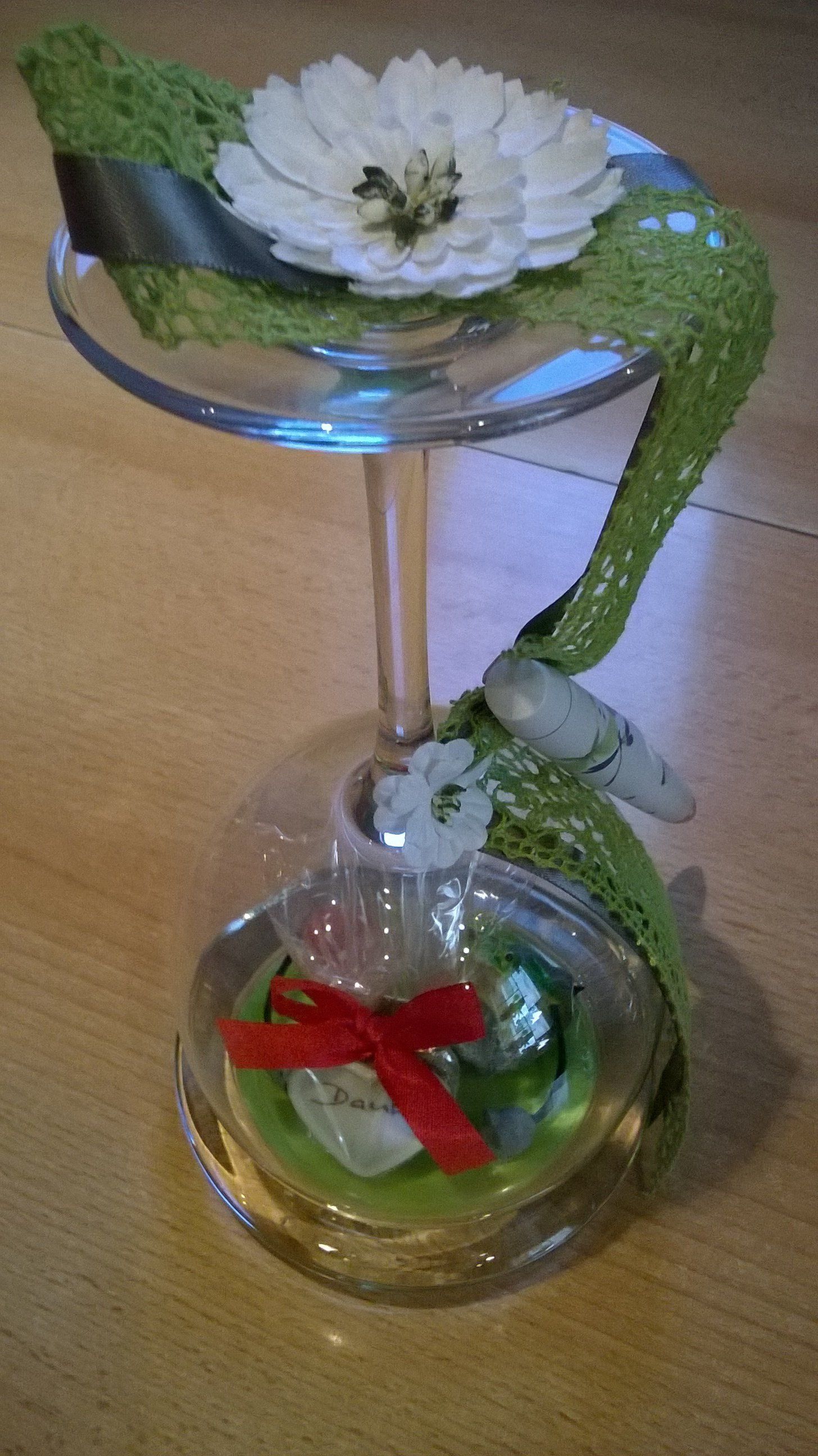 Ein Weinglas mit einer Blume und einer roten Schleife darauf.