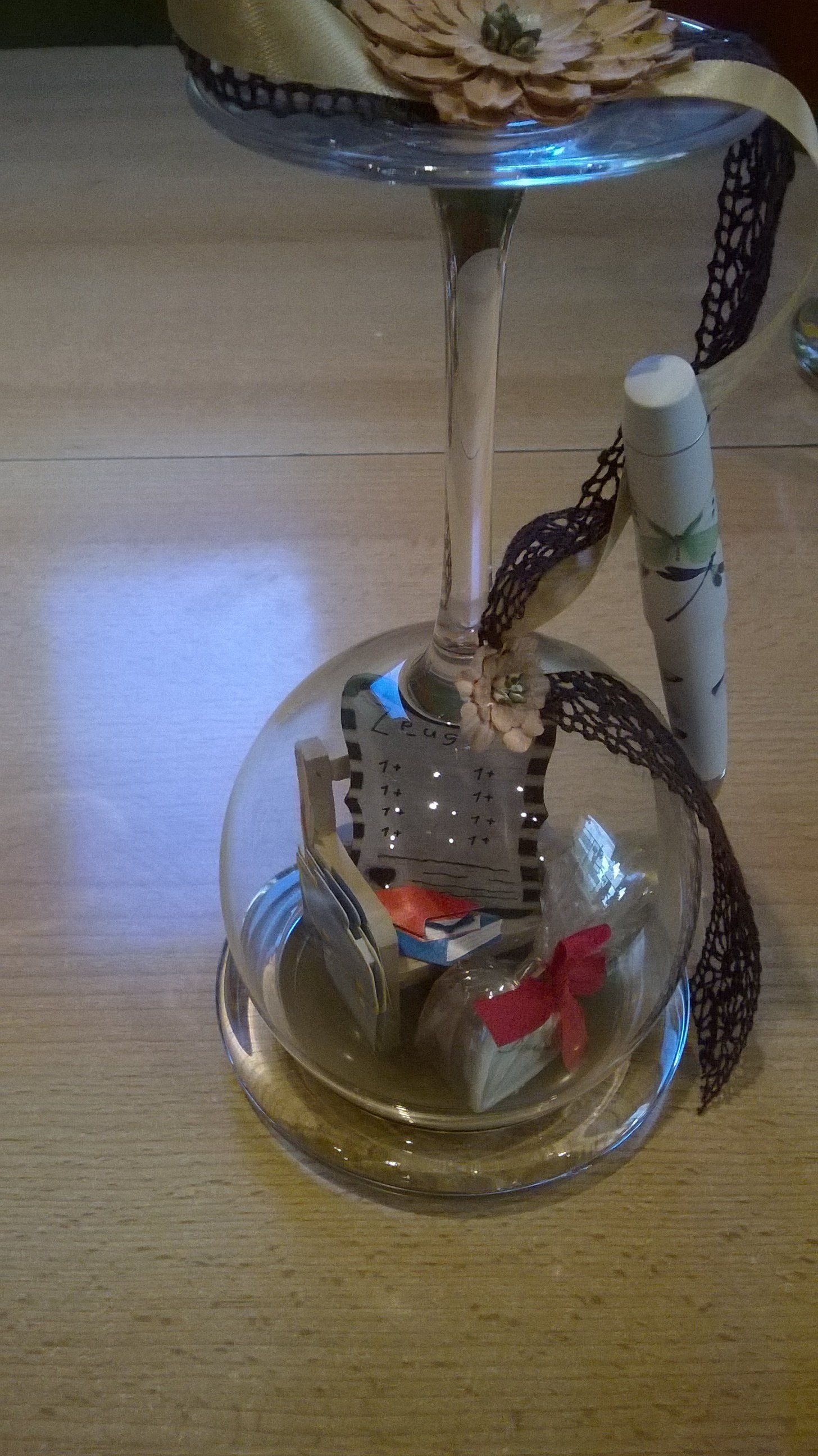 Ein mit Schmuck gefülltes Weinglas und ein Lippenstift auf einem Tisch.