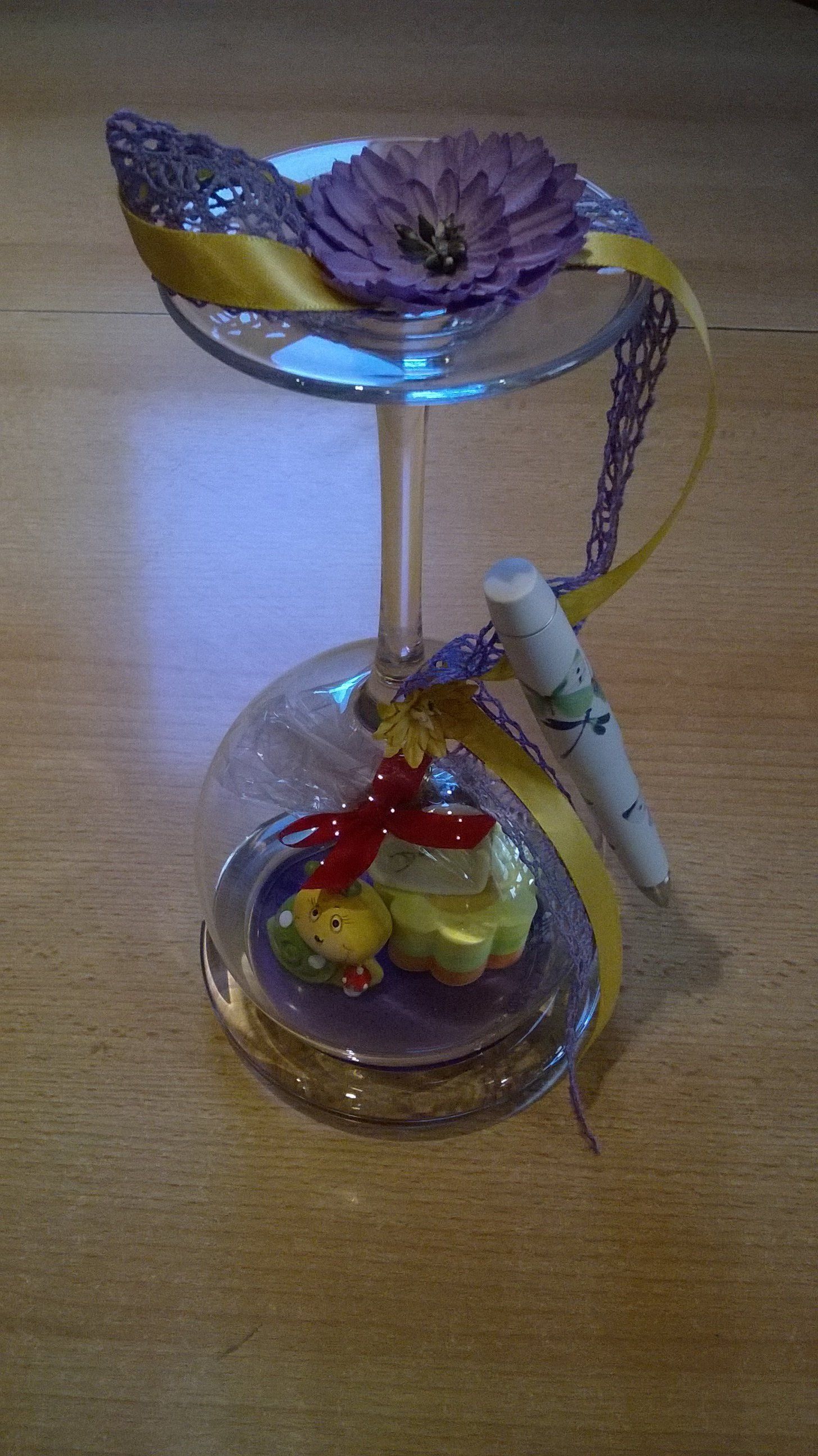 Ein Weinglas mit einer Blume und einem Stift darin steht auf einem Holztisch.