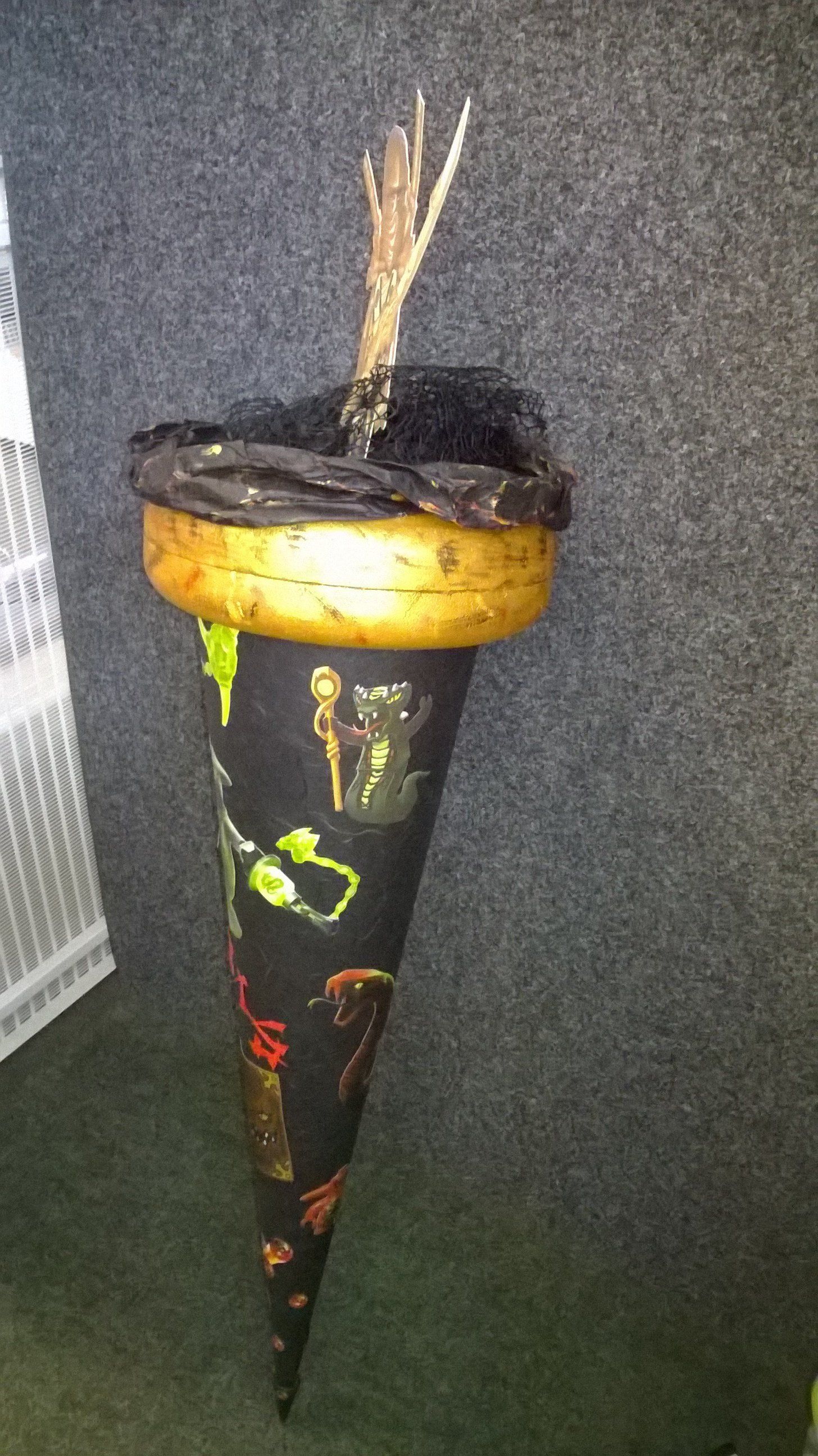 An einer Wand hängt ein schwarzer Kegel mit einem Hexenhut darauf.