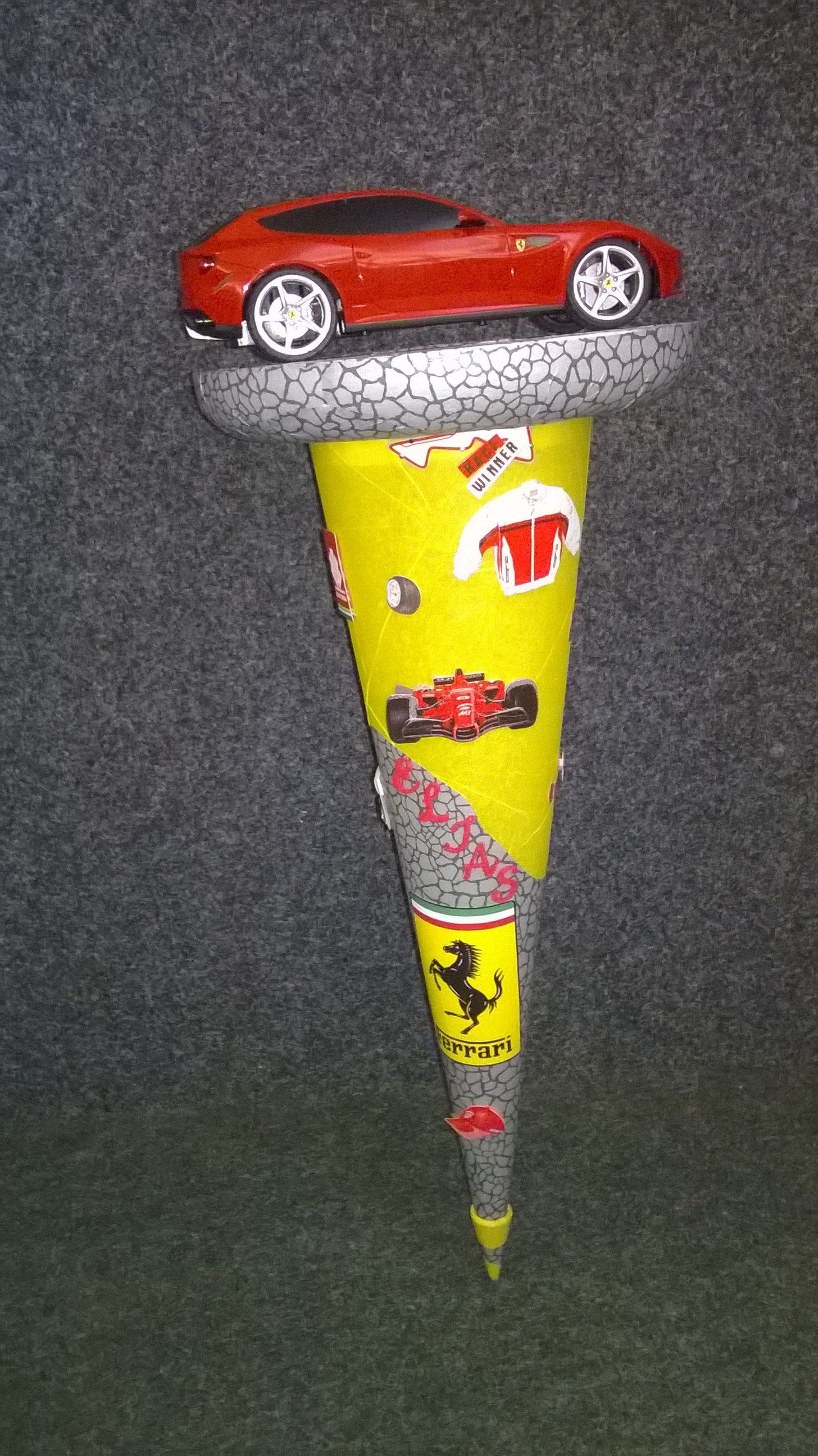 Auf einem gelb-grauen Kegel steht ein Spielzeugauto.