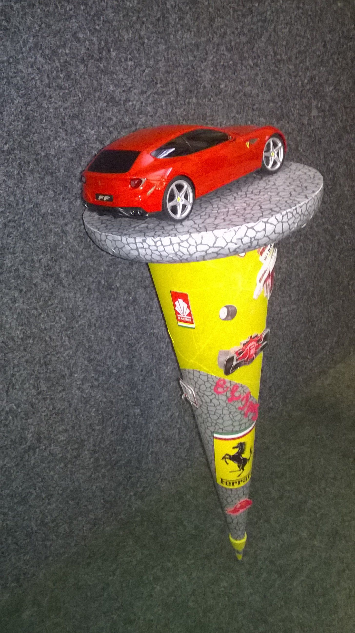 Ein rotes Spielzeugauto steht auf einem gelben Kegel.