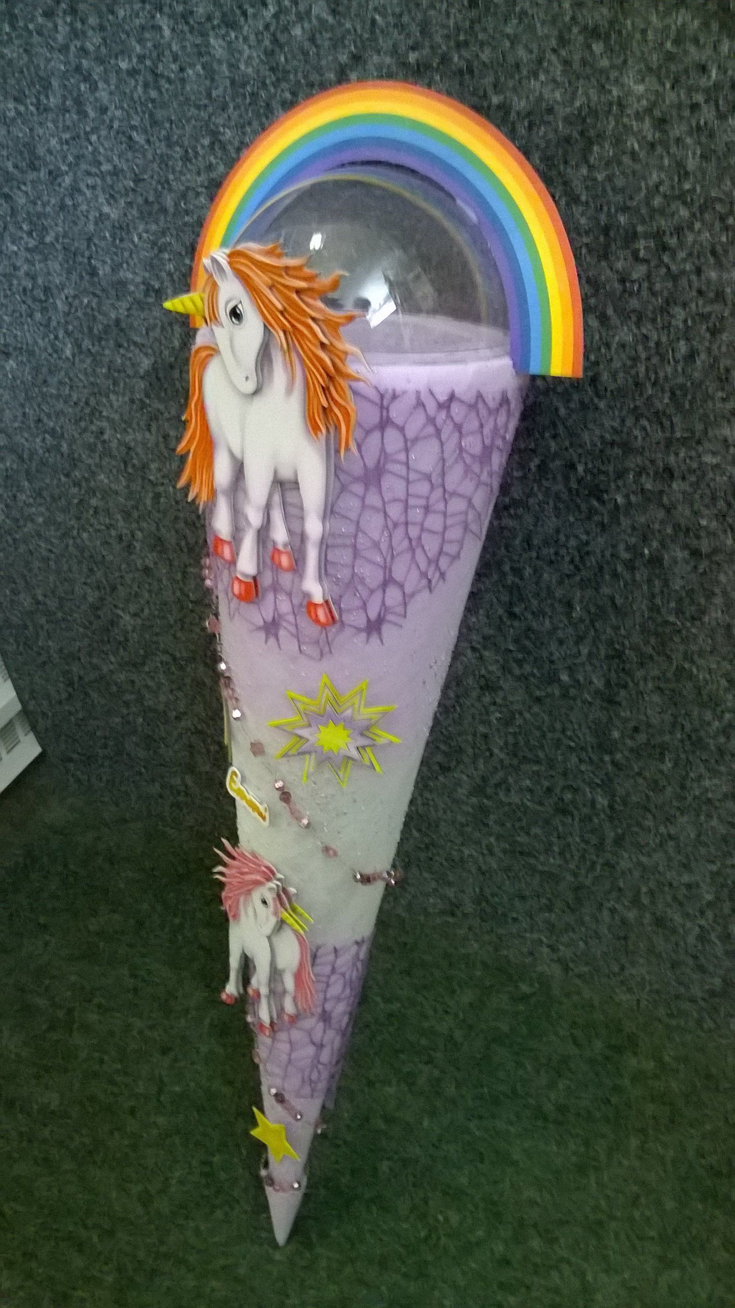 Ein lila Kegel mit einem Einhorn und einem Regenbogen darauf.