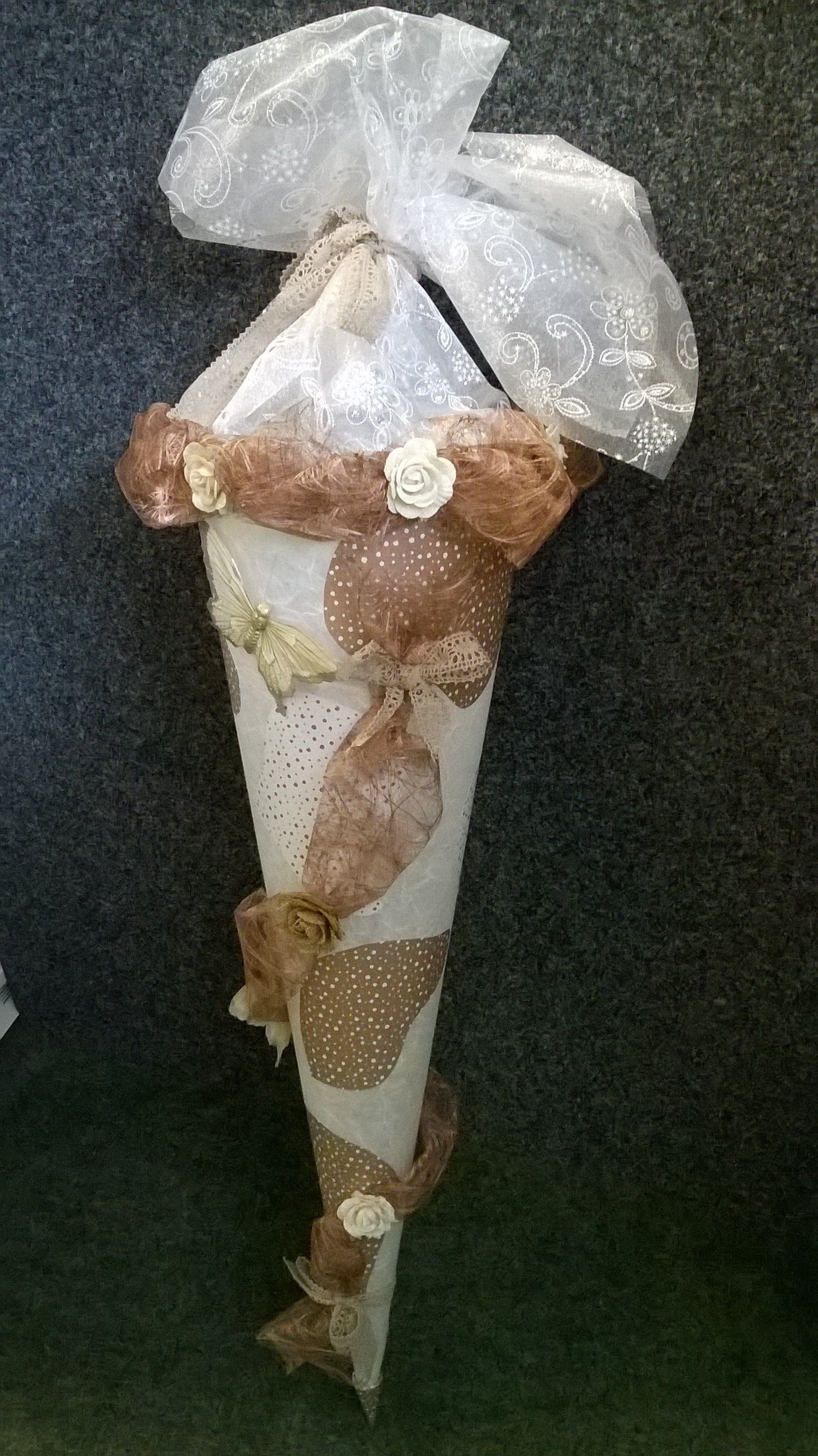 Auf einem Tisch steht ein Kegel mit einer Schleife darauf.