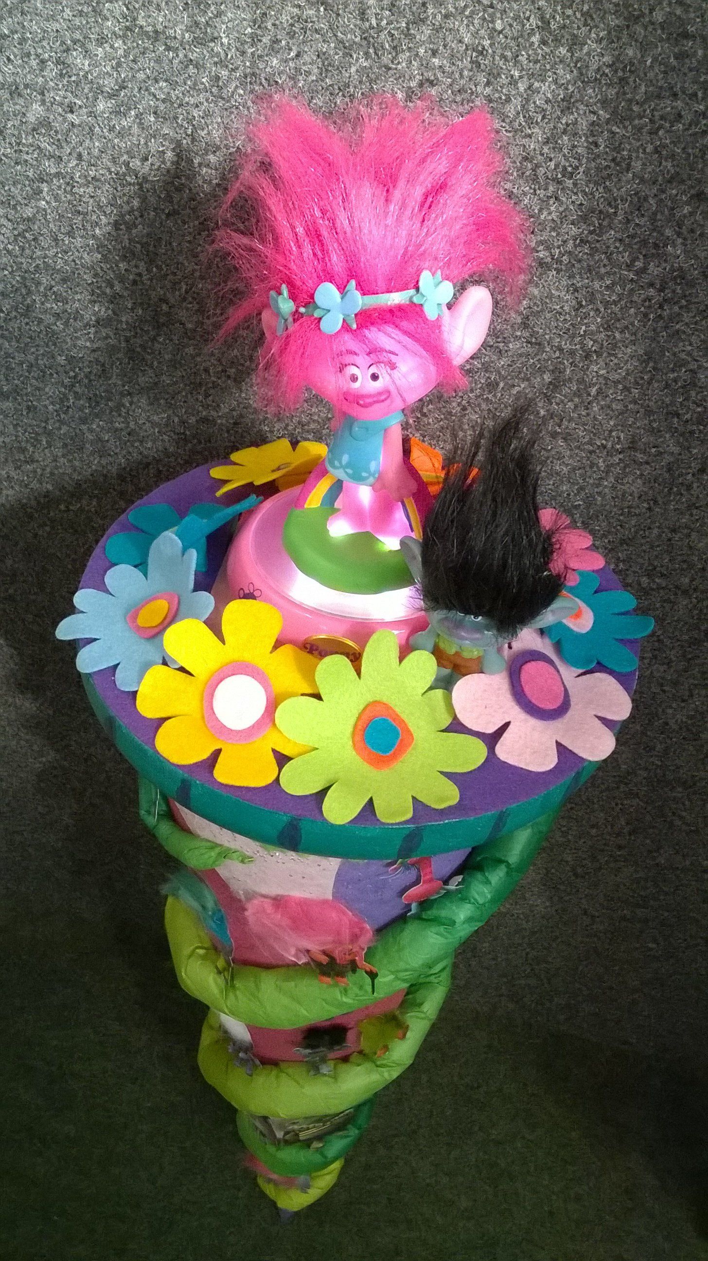 Eine Trollpuppe sitzt auf einem bunten Kegel.