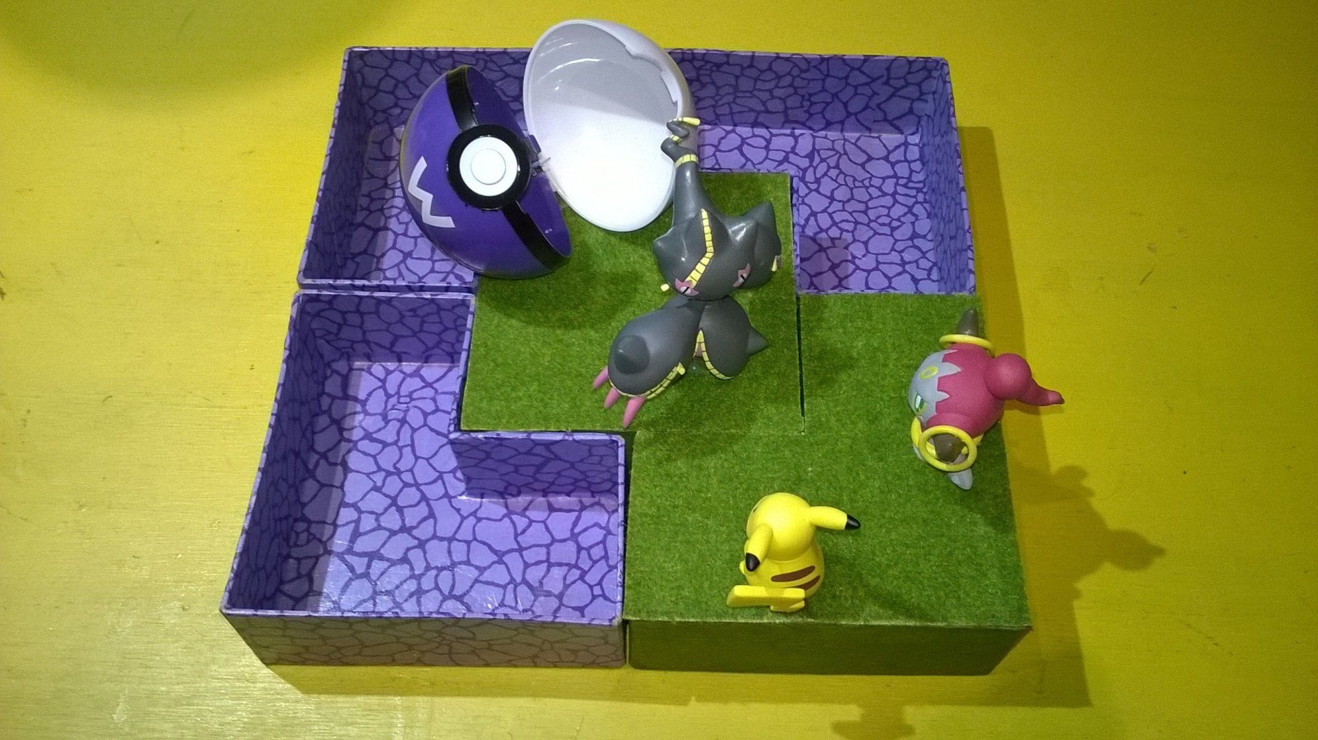 Eine lila Schachtel voller Pokemon-Spielzeuge auf einem Tisch.