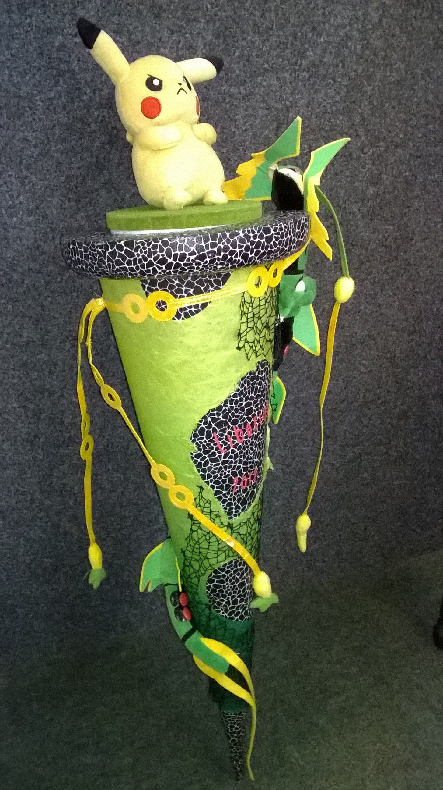 Ein ausgestopftes Pikachu sitzt auf einem grünen Kegel.