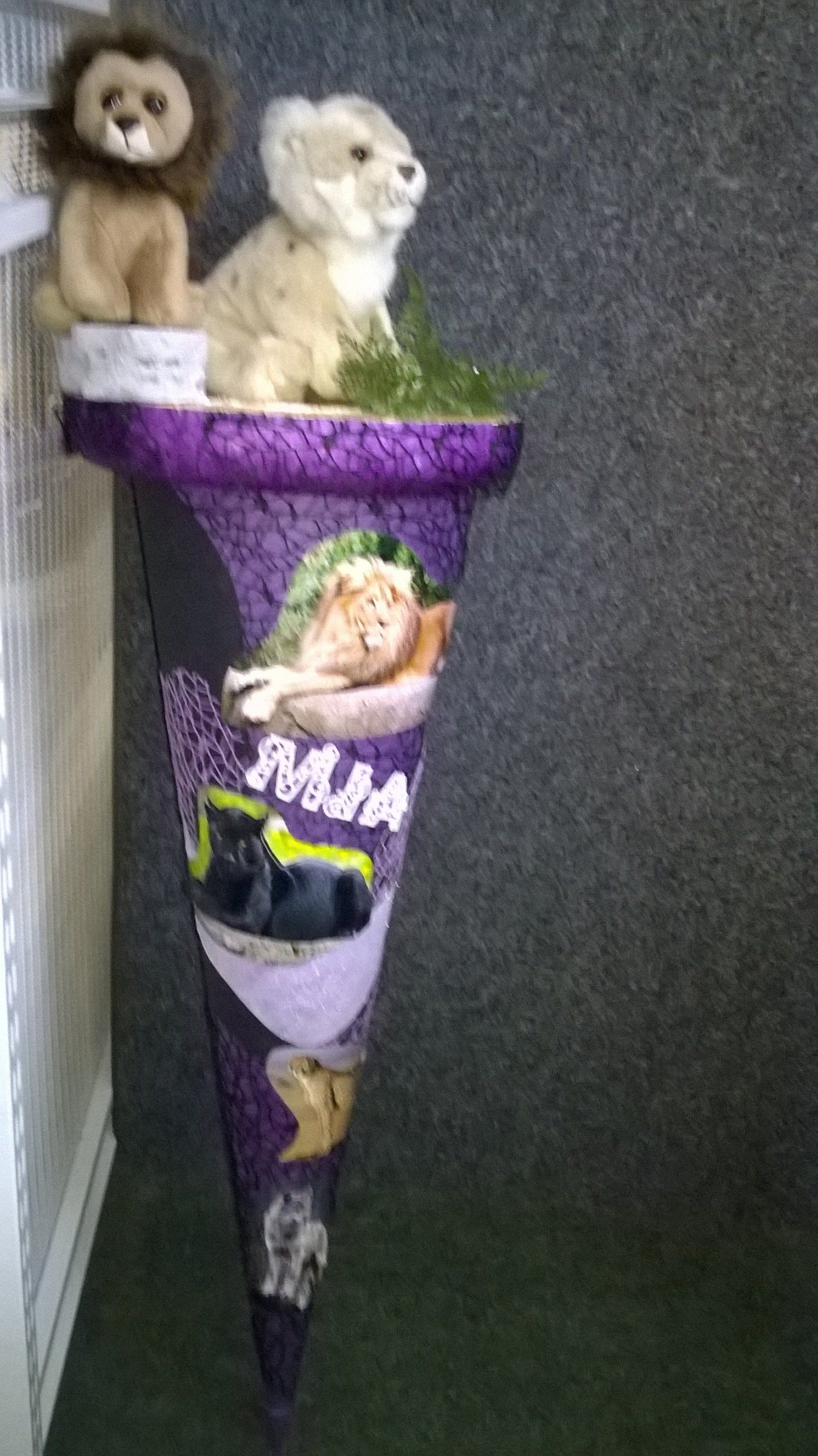 Ein lila Kegel mit Stofftieren obendrauf.