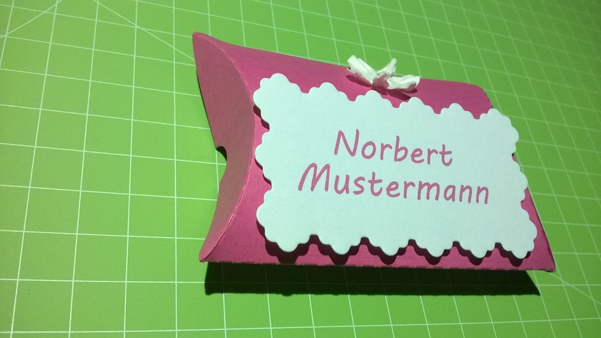 Eine rosa Kissenschachtel mit dem Namen Norbert Mustermann darauf
