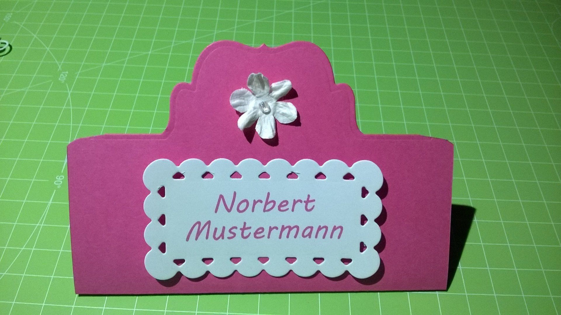 Ein rosa Schild mit dem Namen Norbert Mustermann darauf