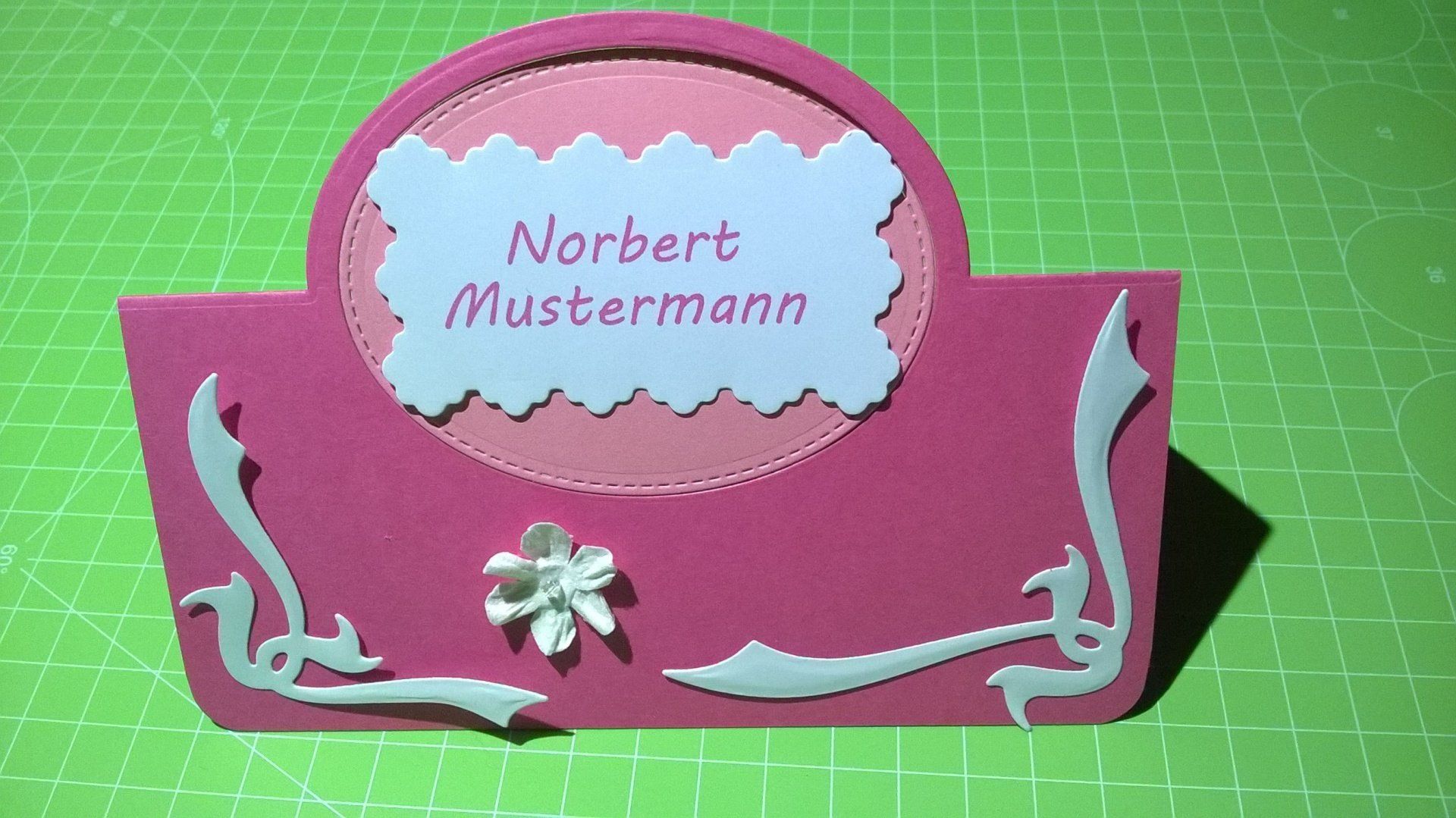 Eine rosa Karte mit dem Namen Norbert Mustermann darauf
