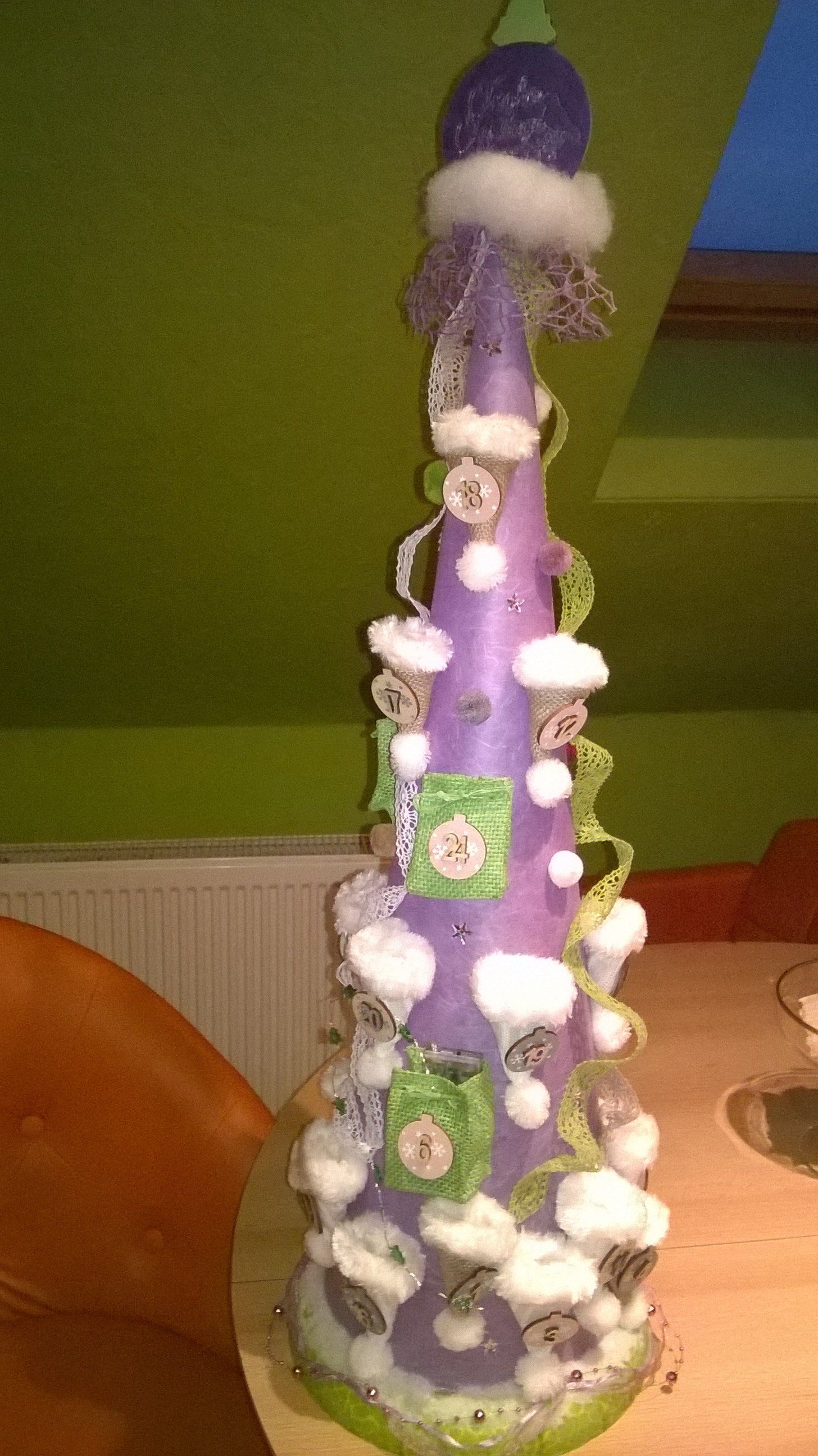 Ein lila Weihnachtsbaum steht auf einem Holztisch.