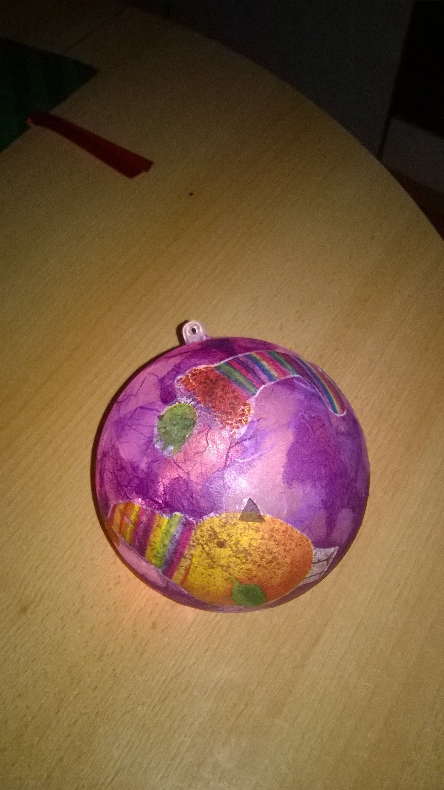 Auf einem Holztisch liegt ein lila Weihnachtsornament.