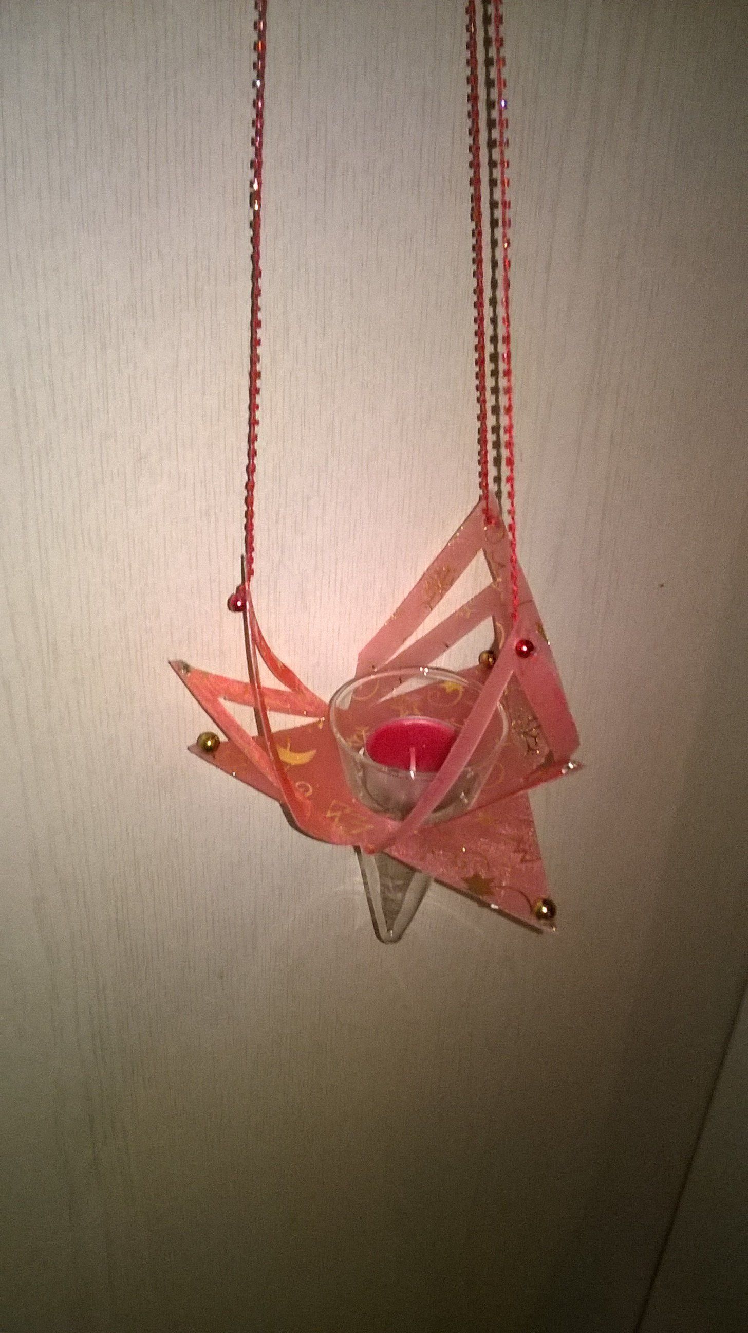 An einer Schnur hängt ein rosa Kerzenhalter in Sternform.
