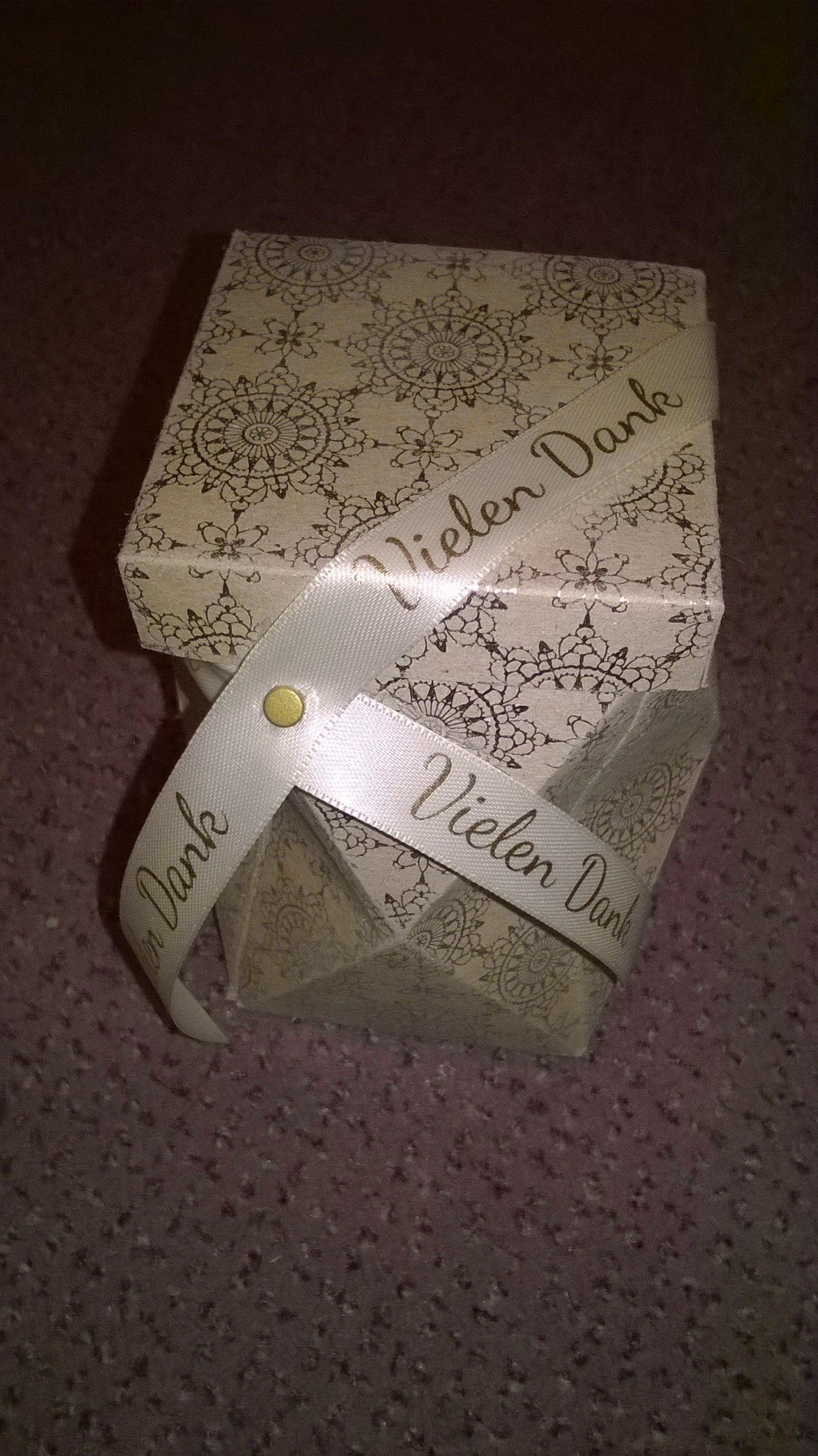 Auf einem Teppich steht eine kleine Schachtel mit einer Schleife darum.