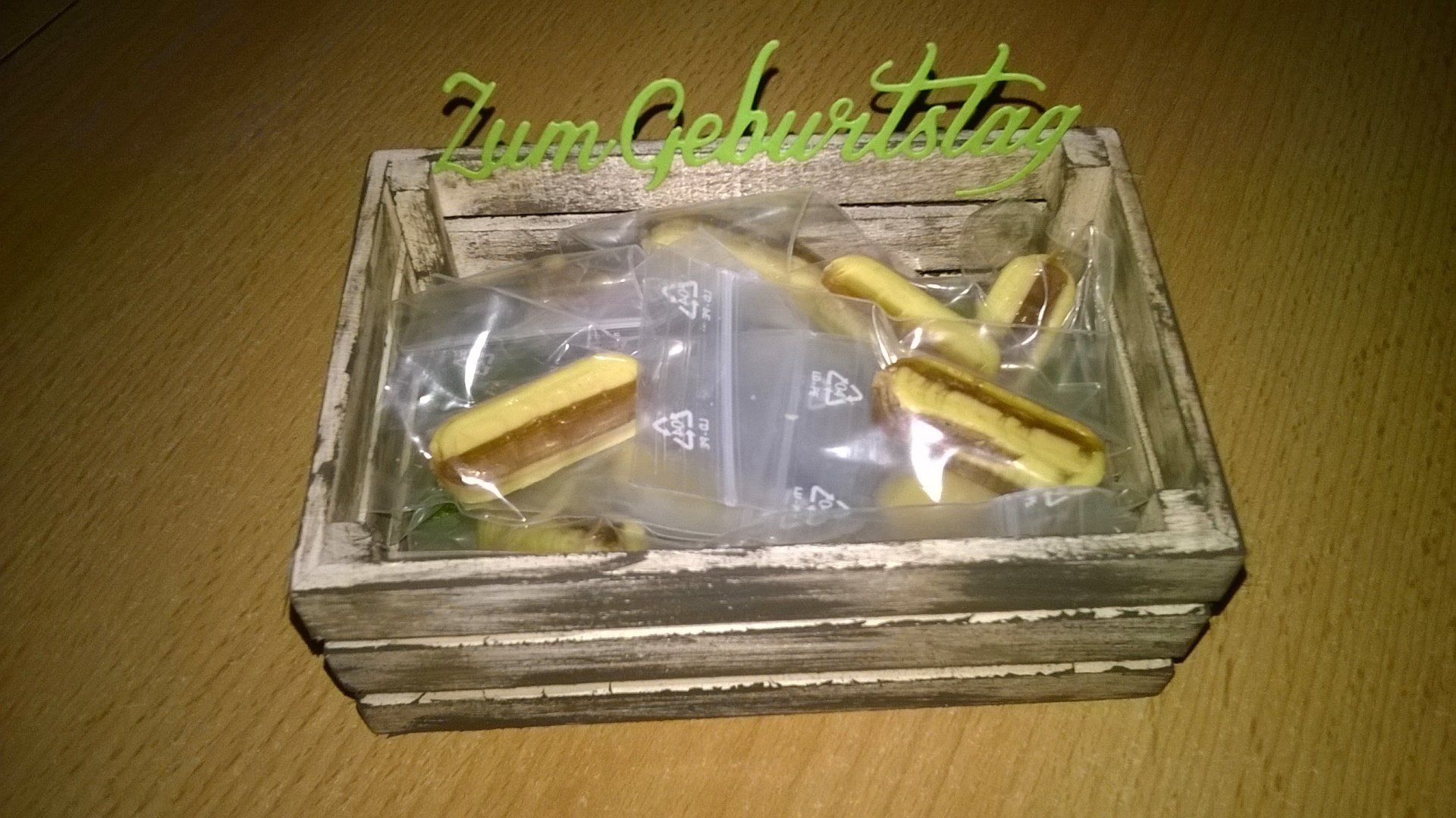 Auf einem Holztisch steht eine Holzschachtel voller Süßigkeiten.