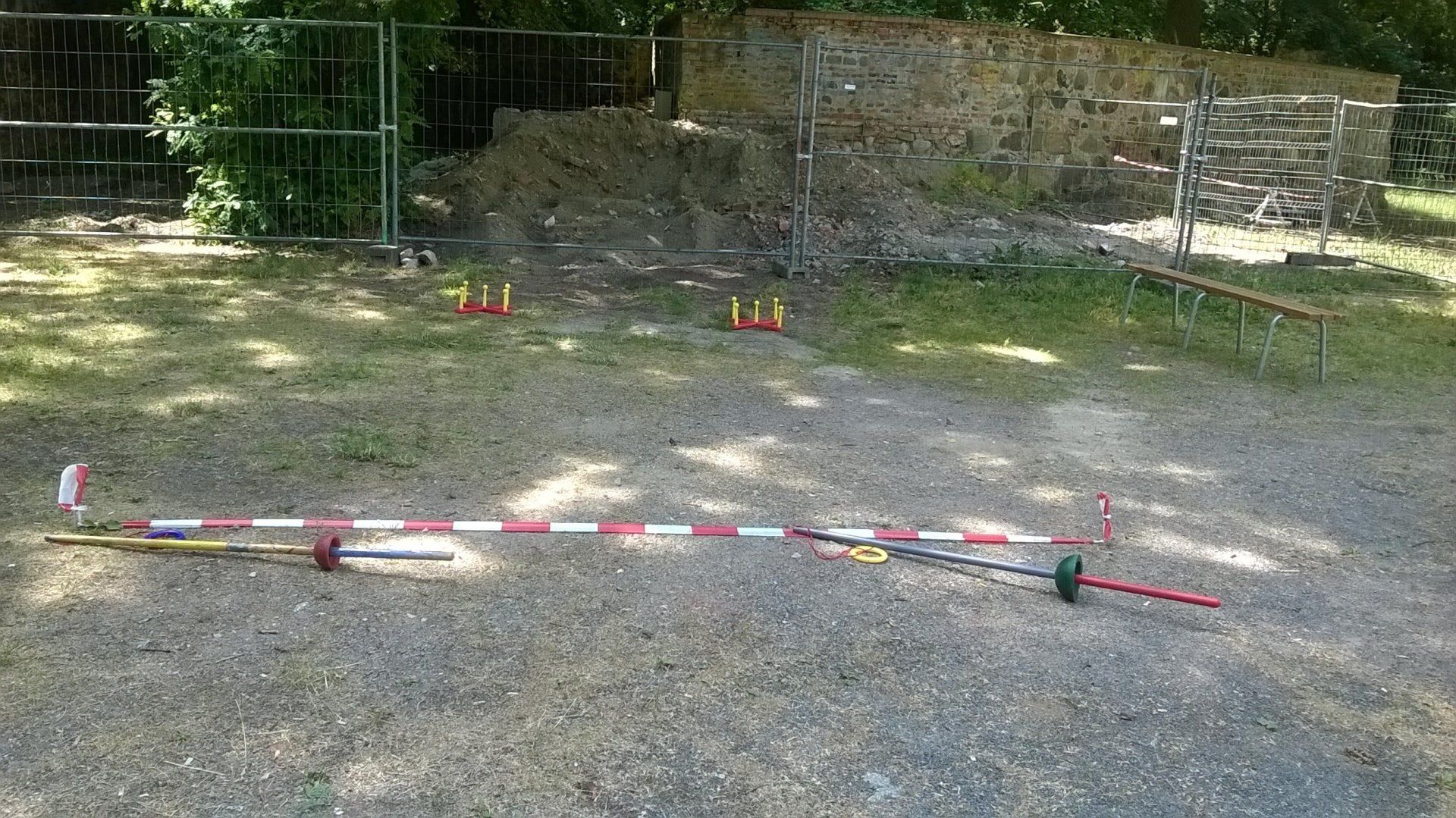 Eine Schotterstraße mit einem Zaun im Hintergrund und einer Reihe von Markierungen darauf.